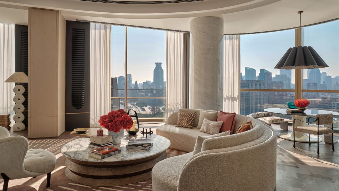 suite with curved couch, dining table, and stunning city views