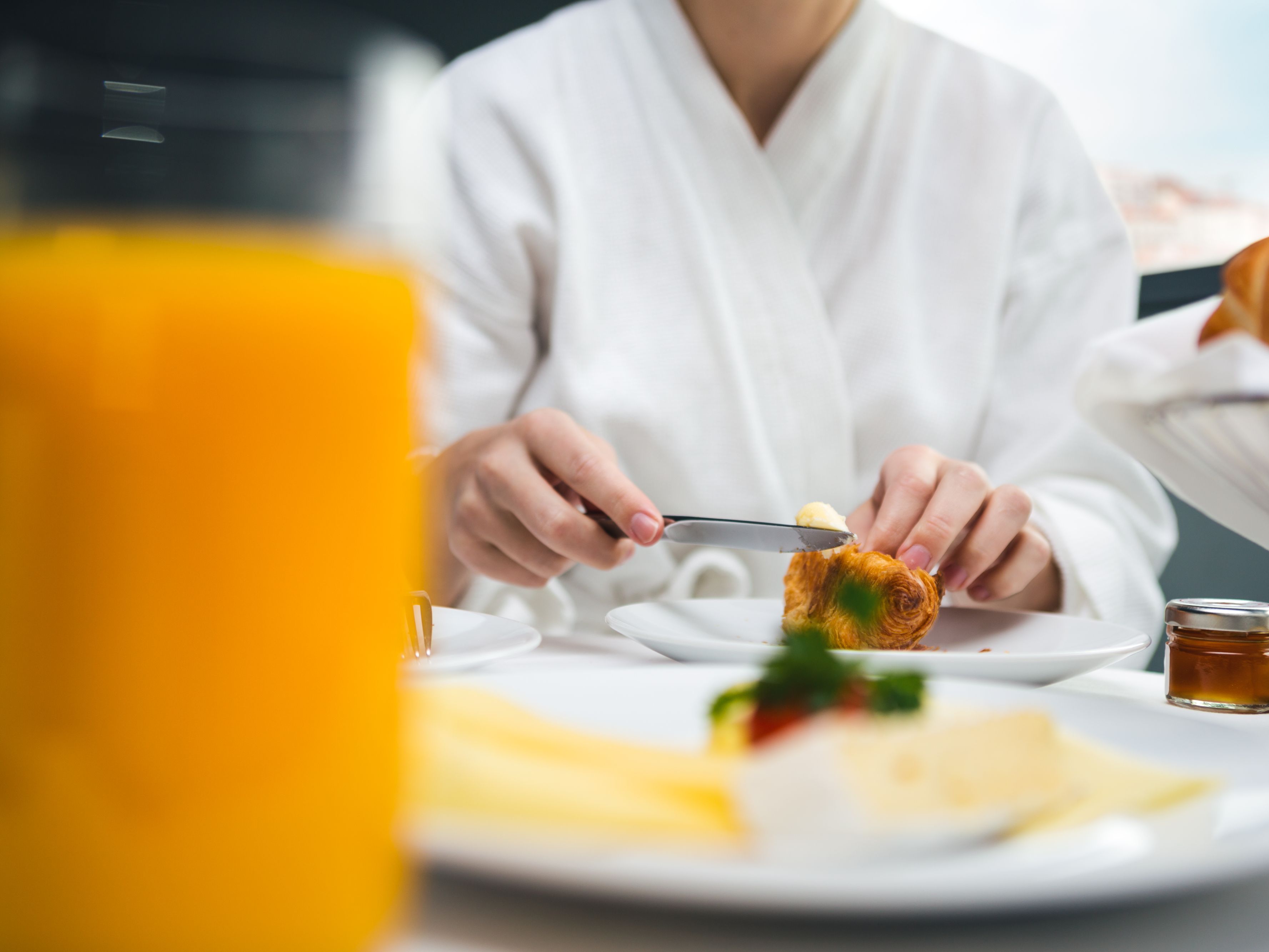 Guest eating breakfast in their hotel room, wearing a robe.