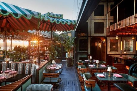 Outdoor restaurant terrace with striped awnings and sunset views