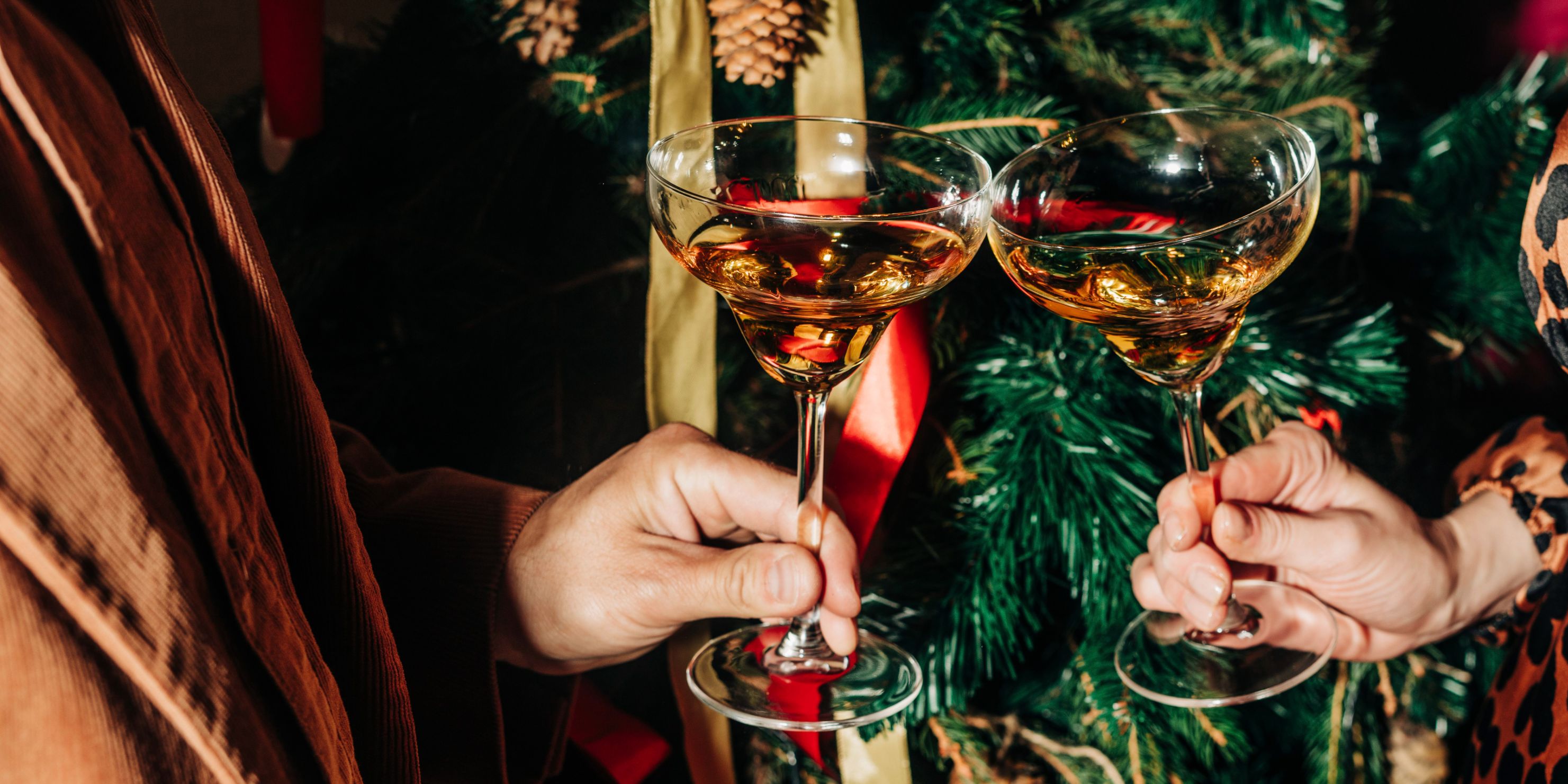 people holding cocktails in front of Christmas tree