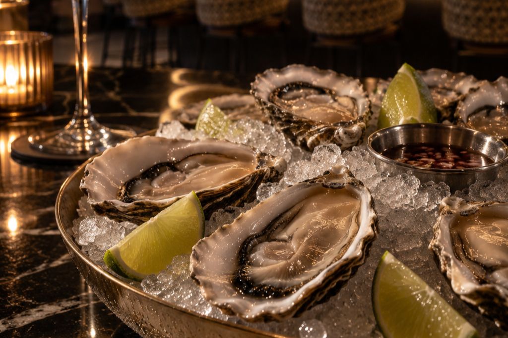 Fresh oysters on ice with lemon wedges and seafood sauces