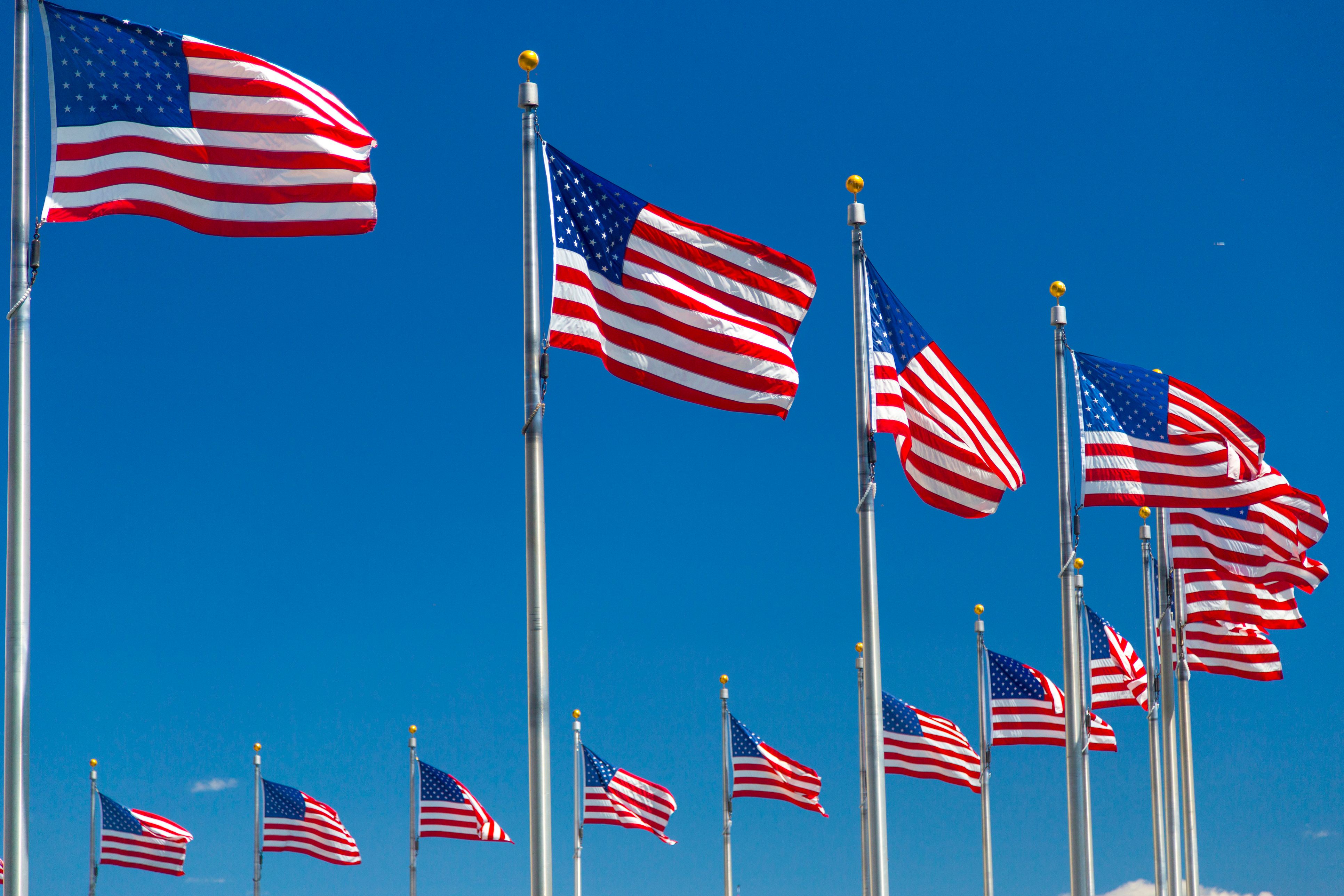 American flags displayed on poles beneath a bright blue sky