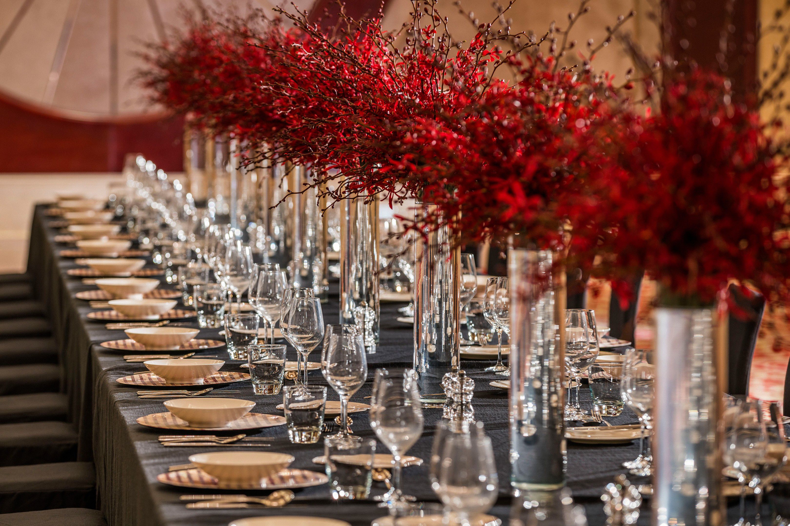 Elegant banquet table with red floral centerpieces and place settings