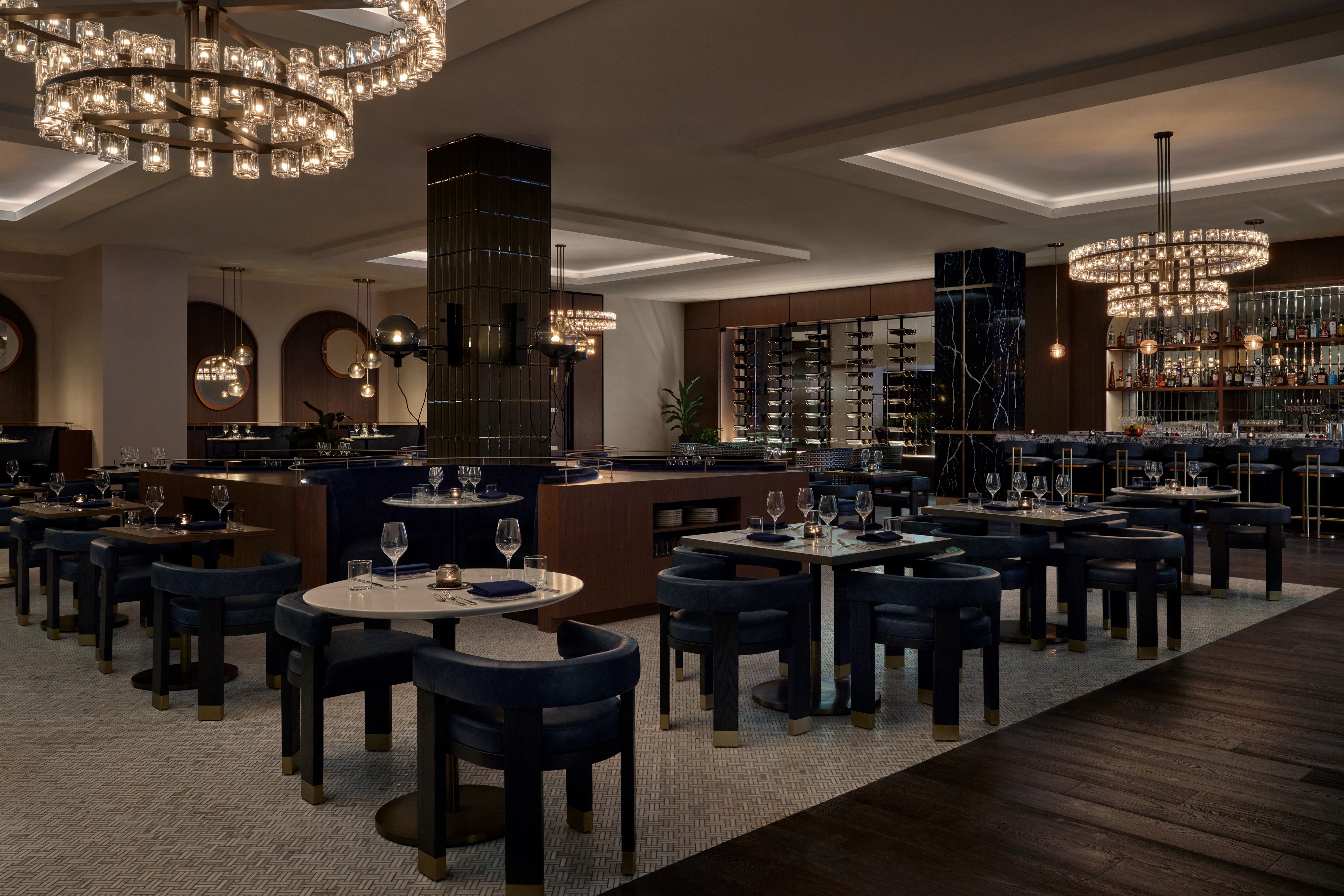 Elegant hotel restaurant with contemporary seating, statement chandeliers, and a stylish bar area