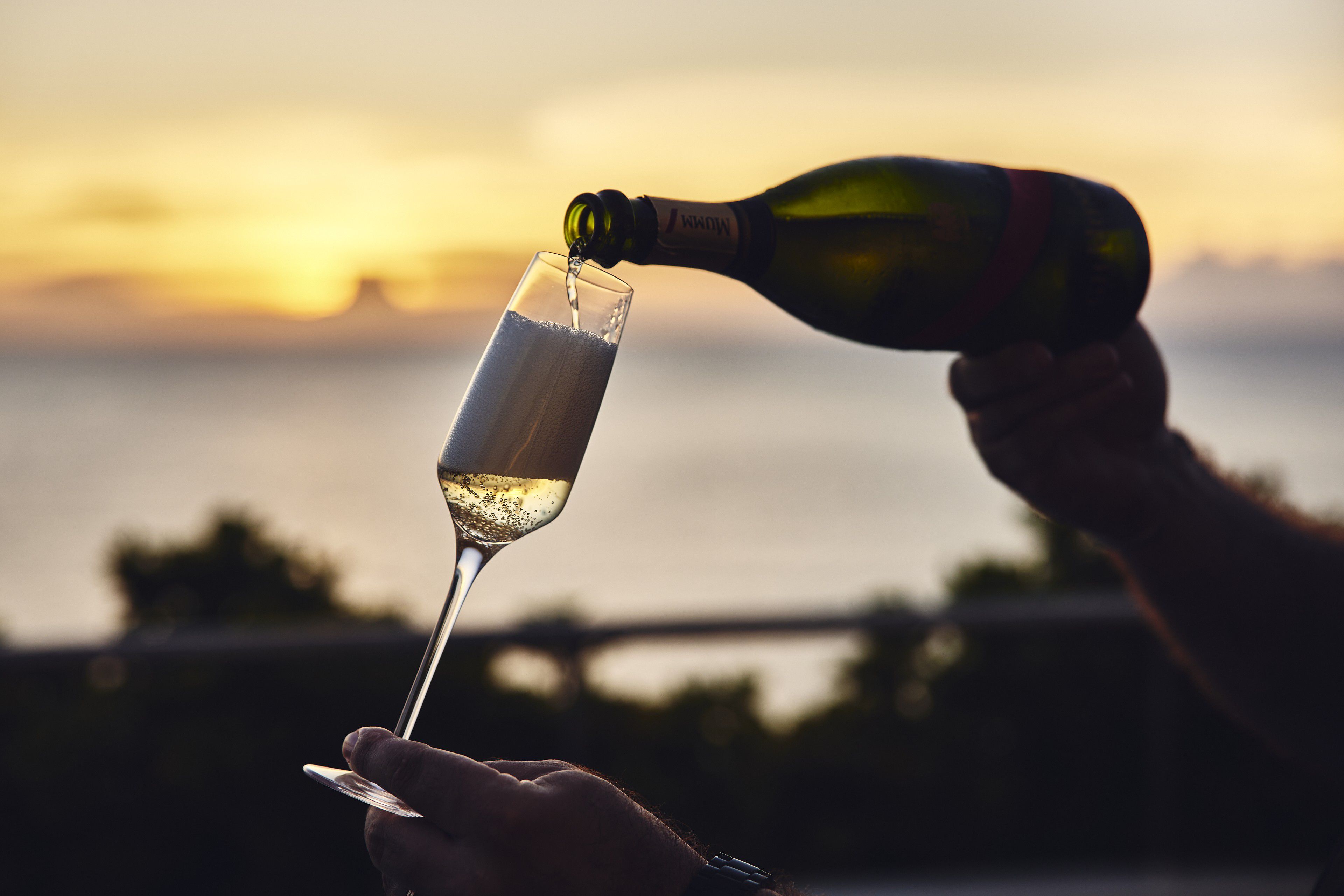 Sparkling wine poured into a flute at sunset