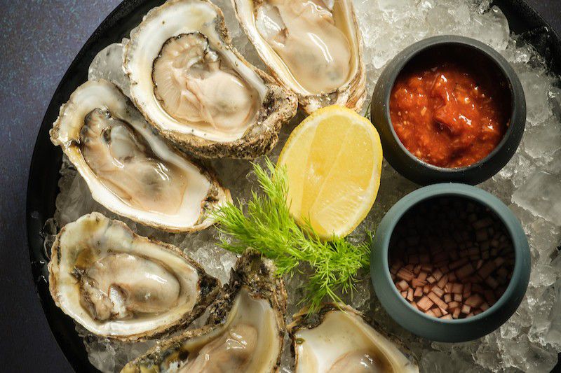 Fresh oysters on ice with lemon wedges and seafood sauces