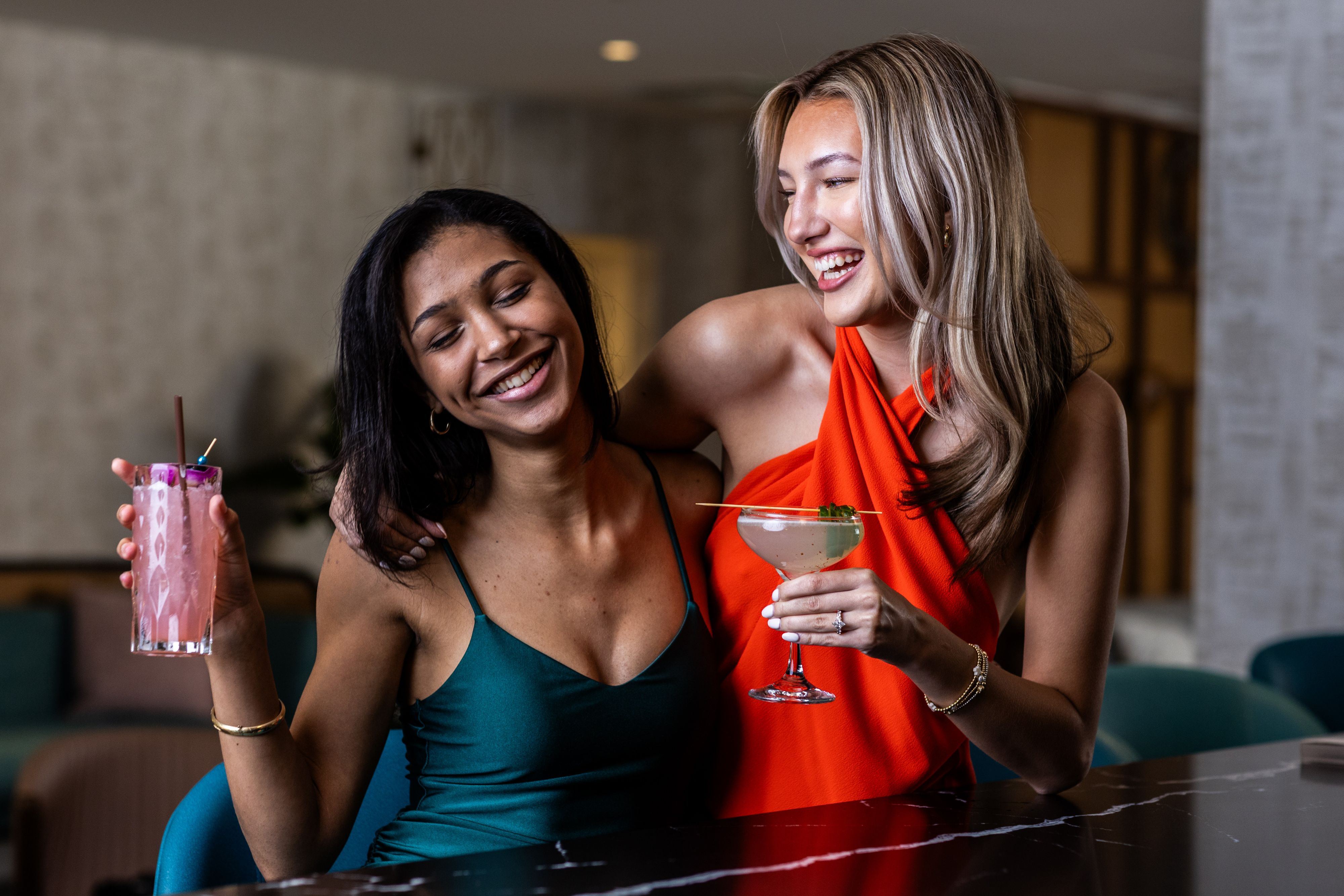 Two guests enjoying cocktails together at a hotel bar or lounge.