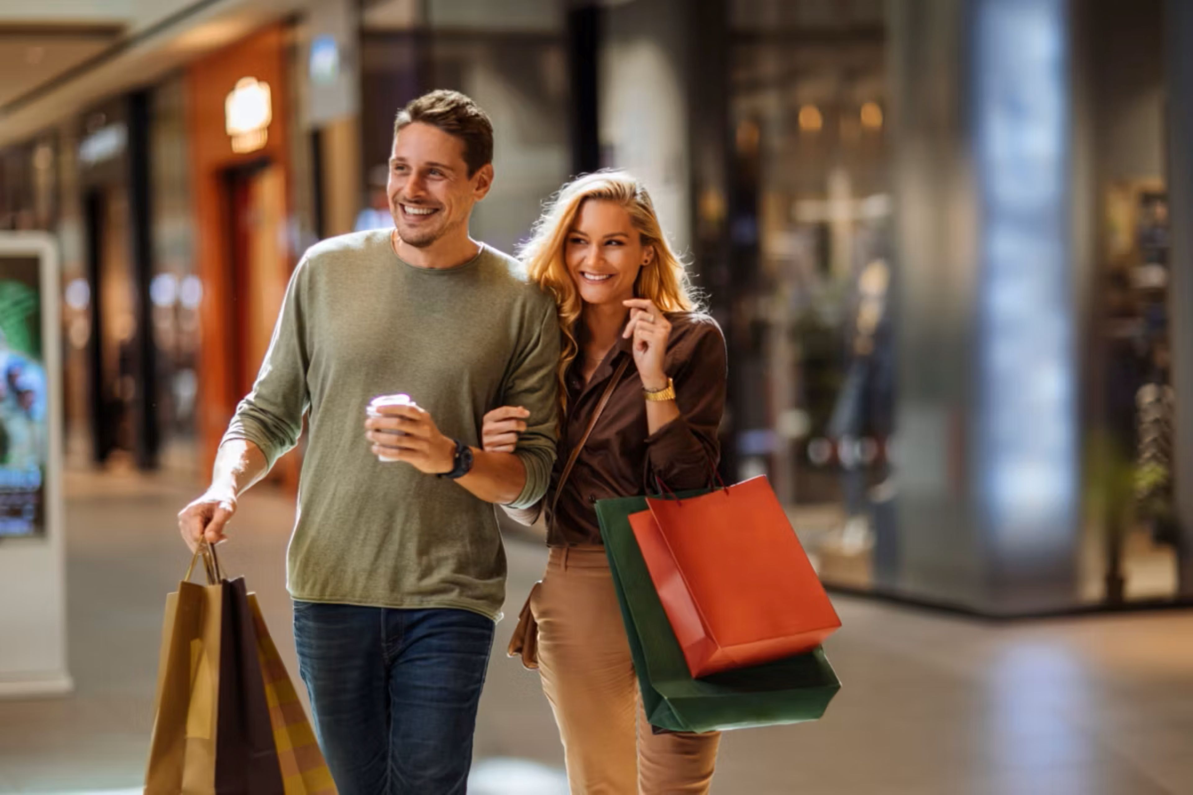 Couple carrying shopping bags while walking through an indoor mall