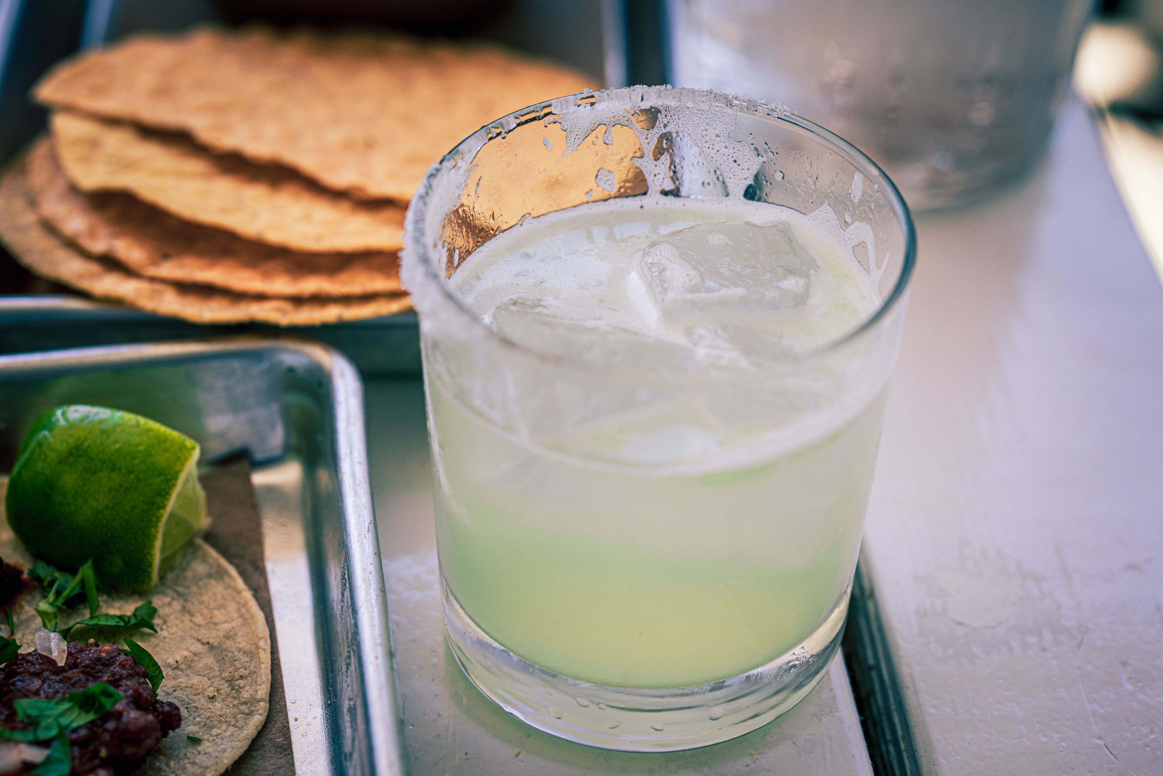 Margarita served alongside tacos and fresh lime wedges.