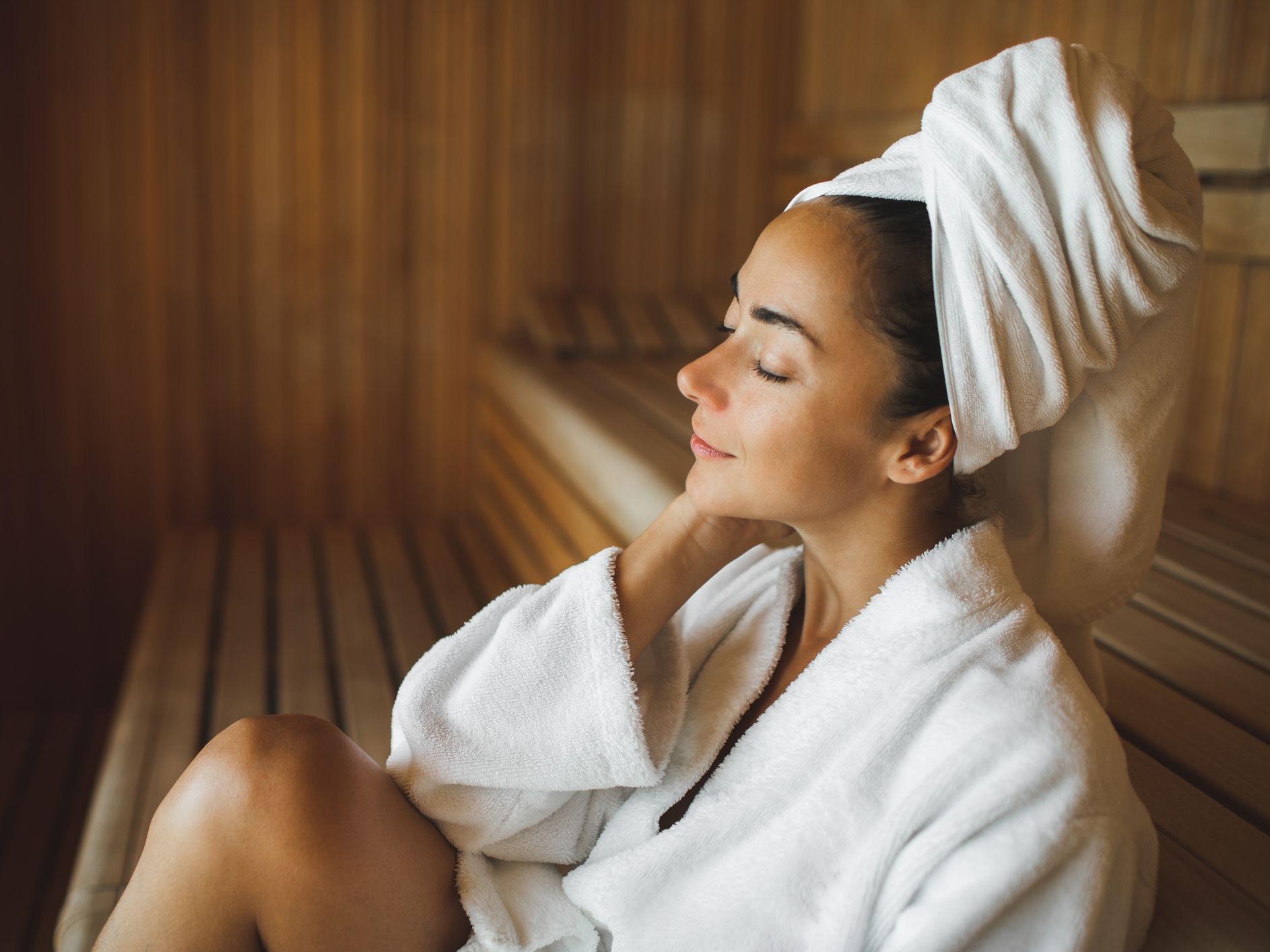 Woman in a robe sitting in a sauna.