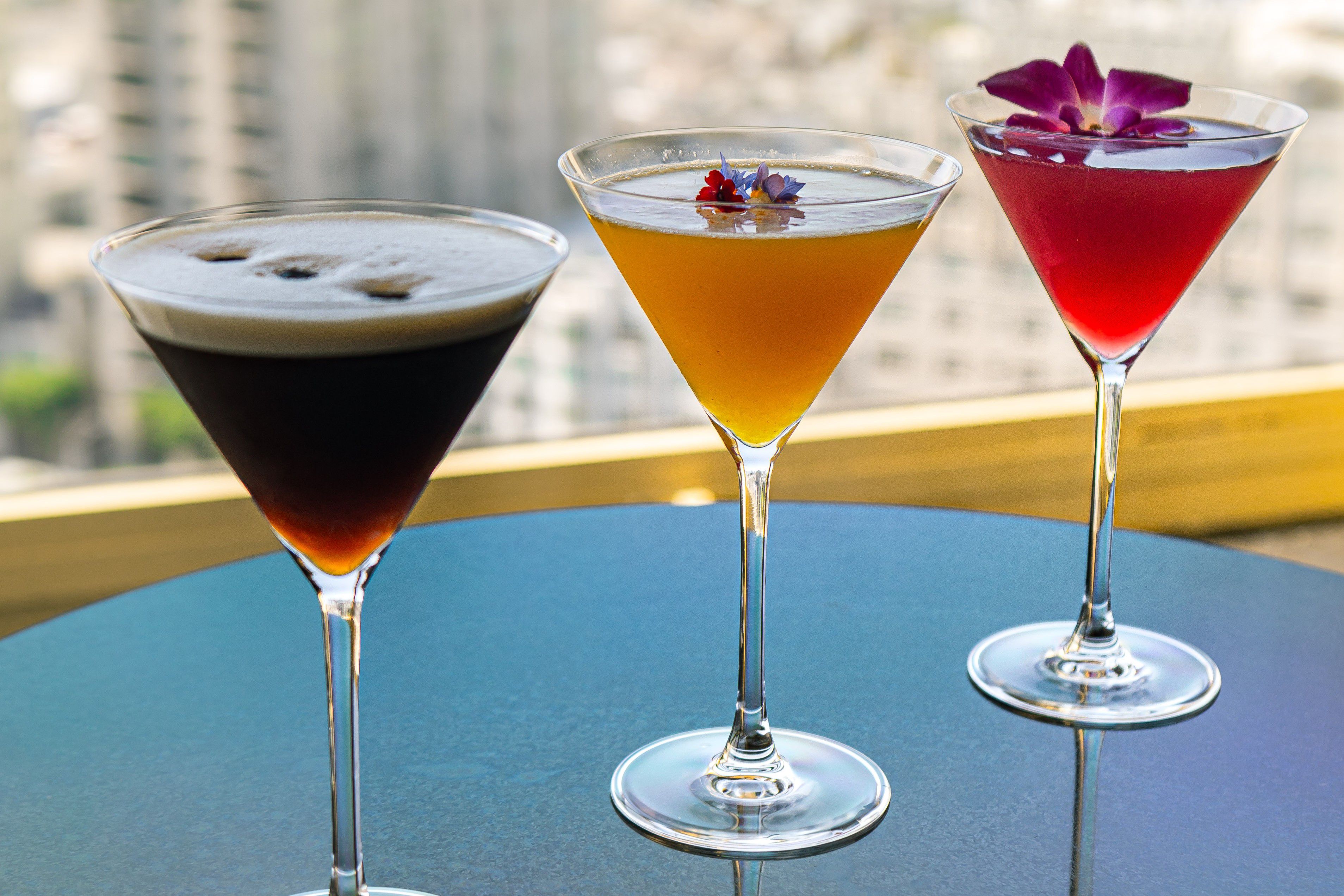 Three martinis on a table overlooking a city skyline