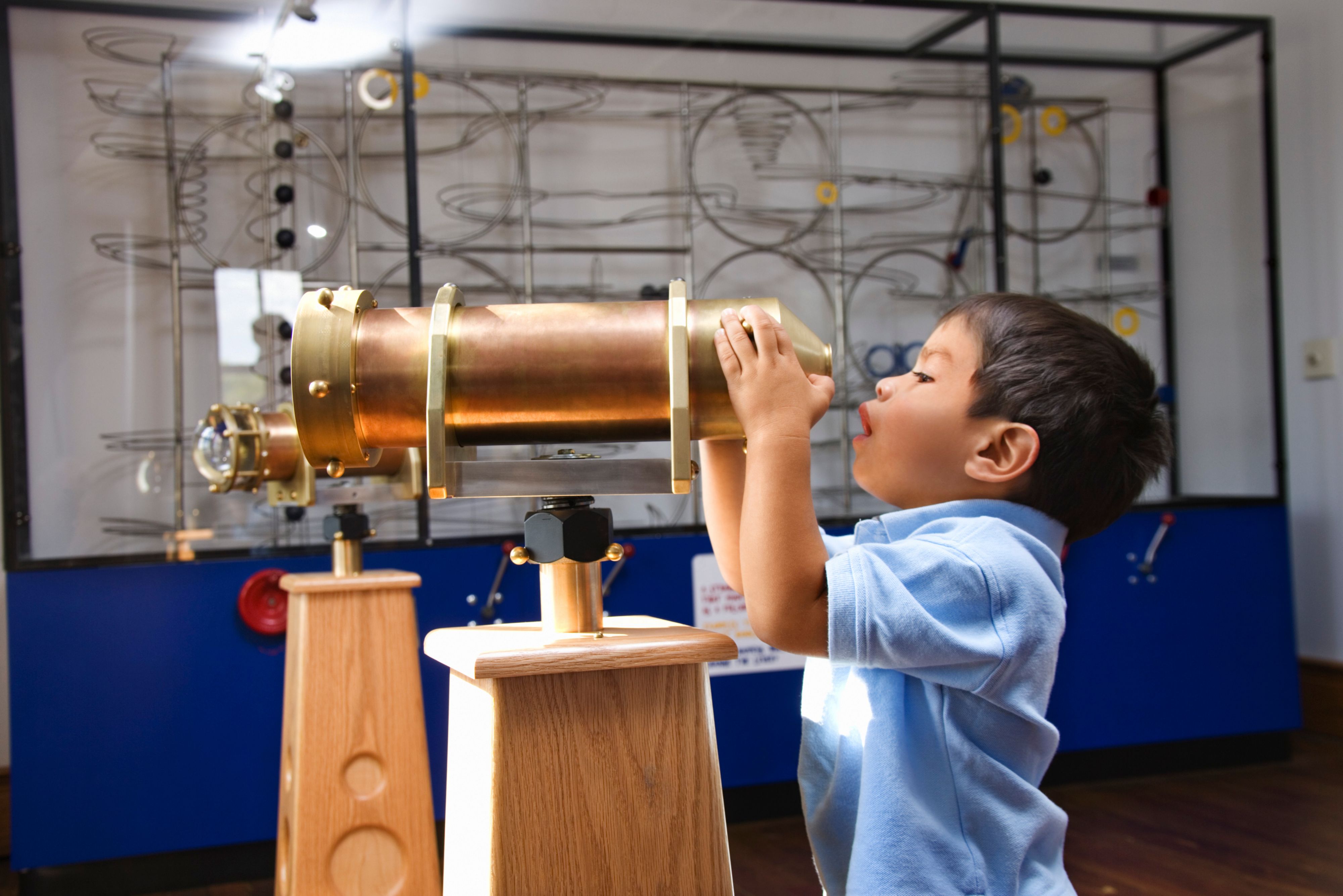 Child looking through golden telescope at a children's museum
