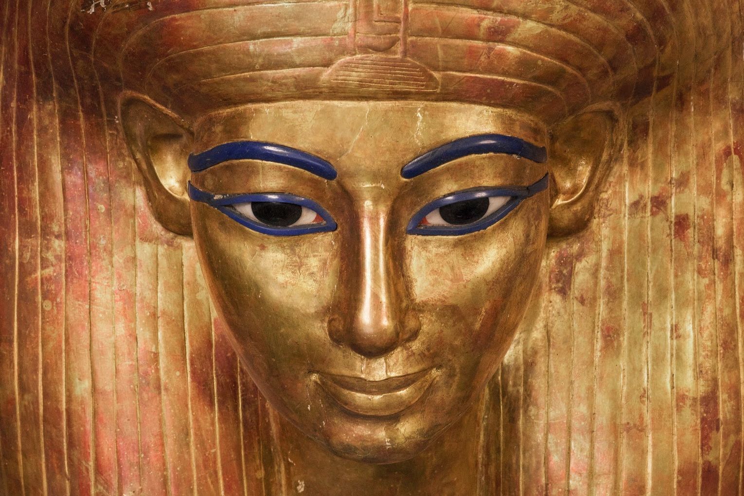 Close up on the golden face of a pharoah statue.