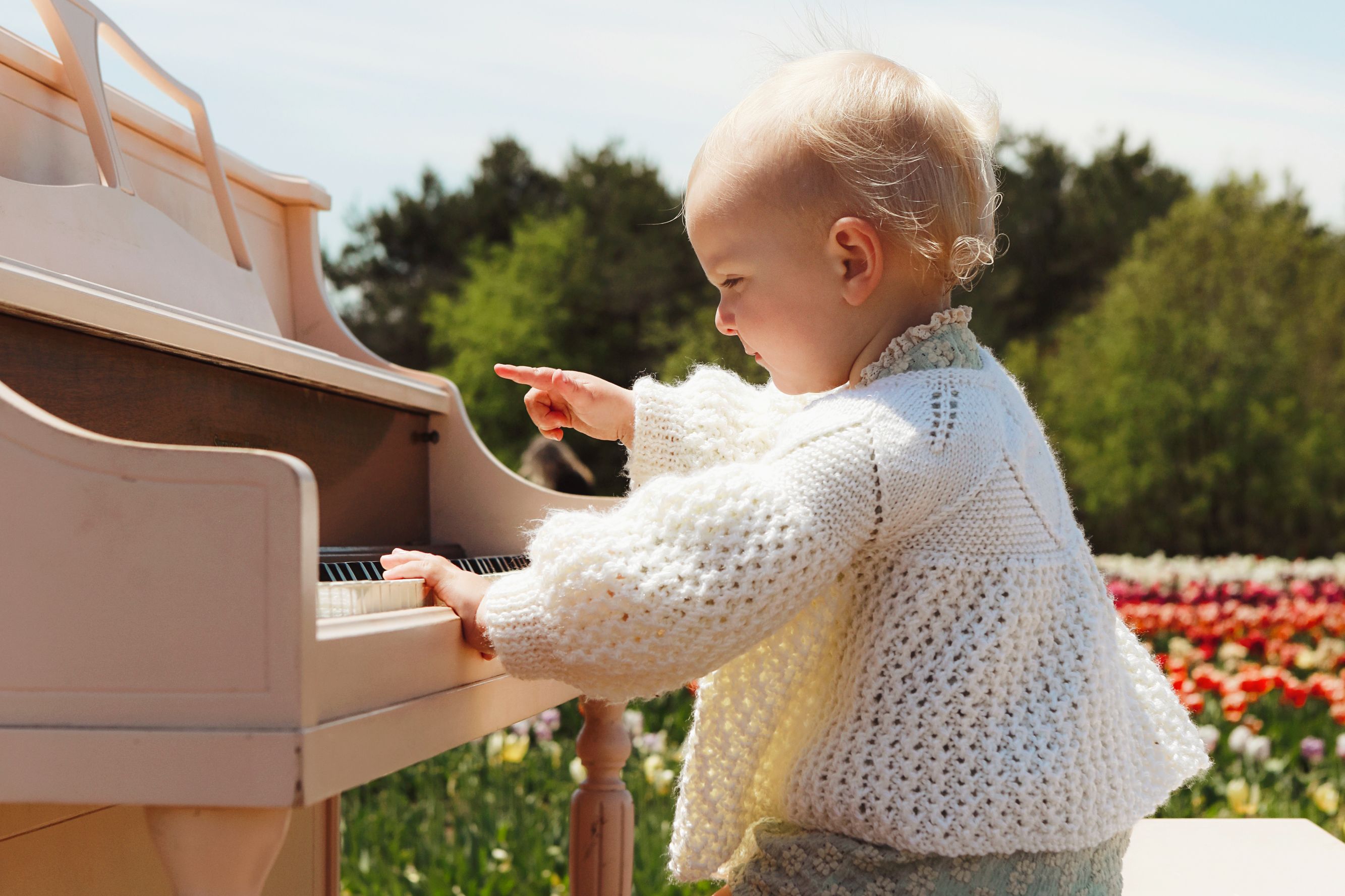 Child playing a piano in a flower garden.