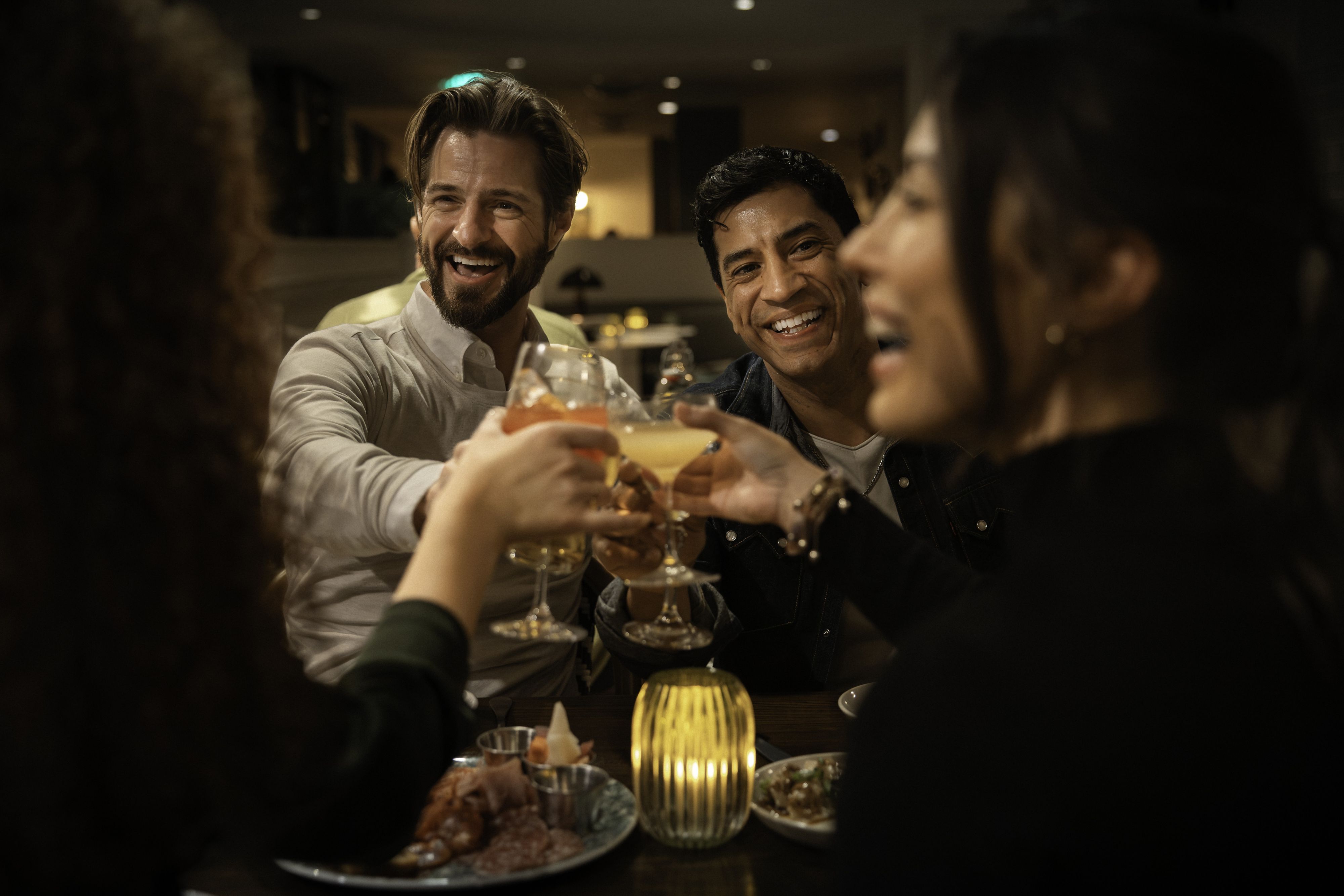 Guests raising cocktails while dining at a restaurant table