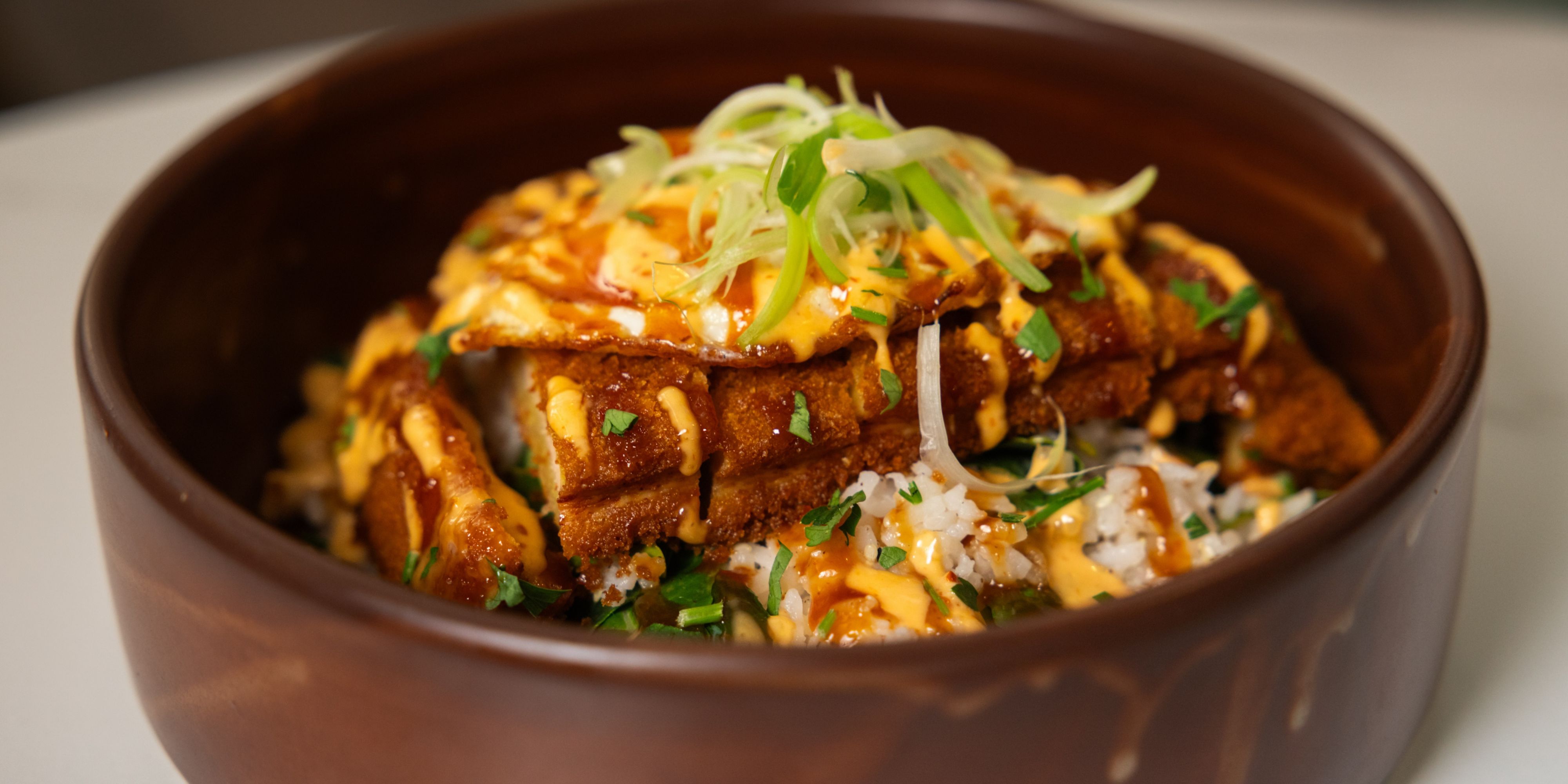 Crispy fried chicken served over rice with sauce and herbs