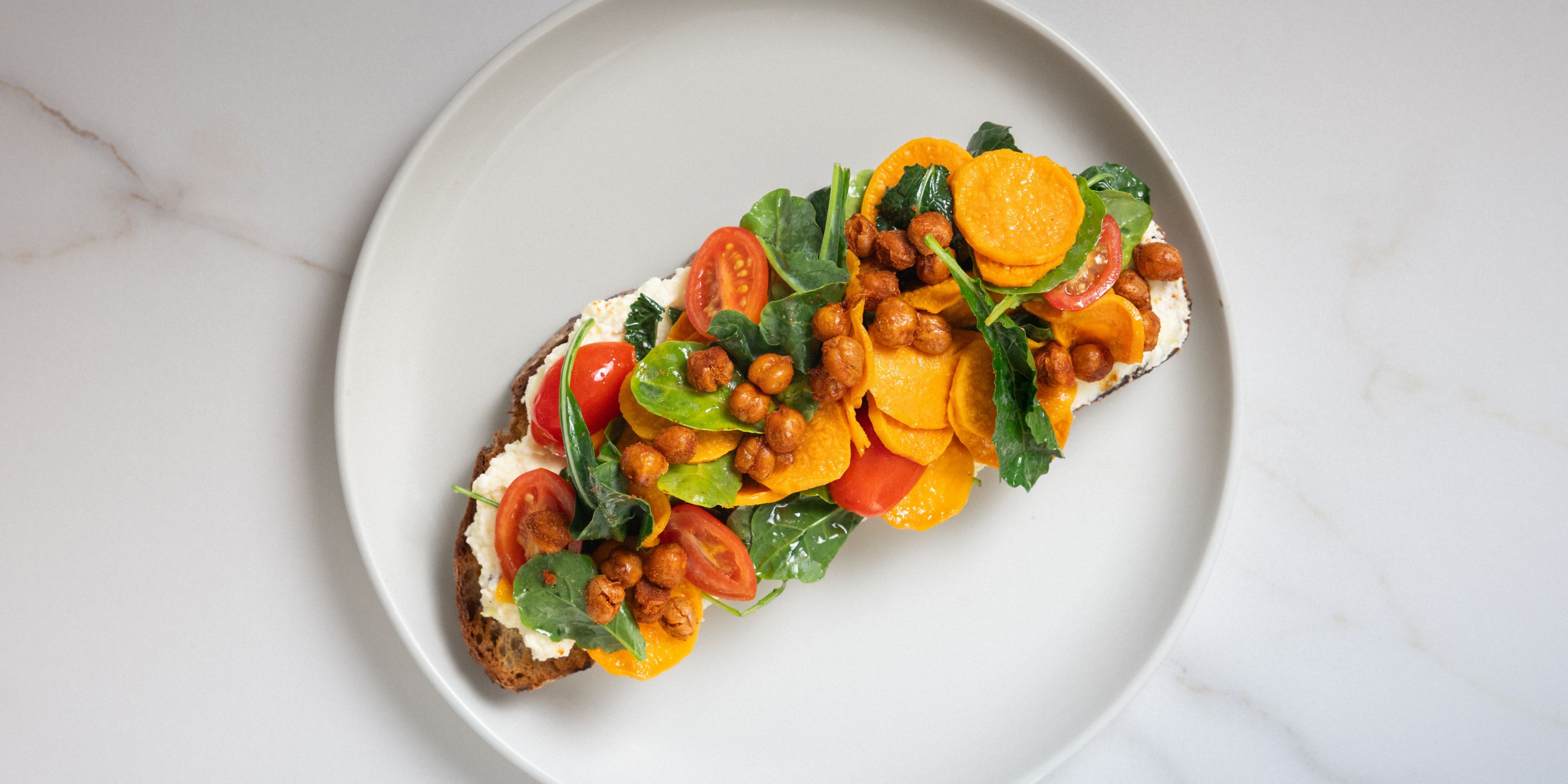 Open-faced toast topped with roasted chickpeas, greens, and tomatoes