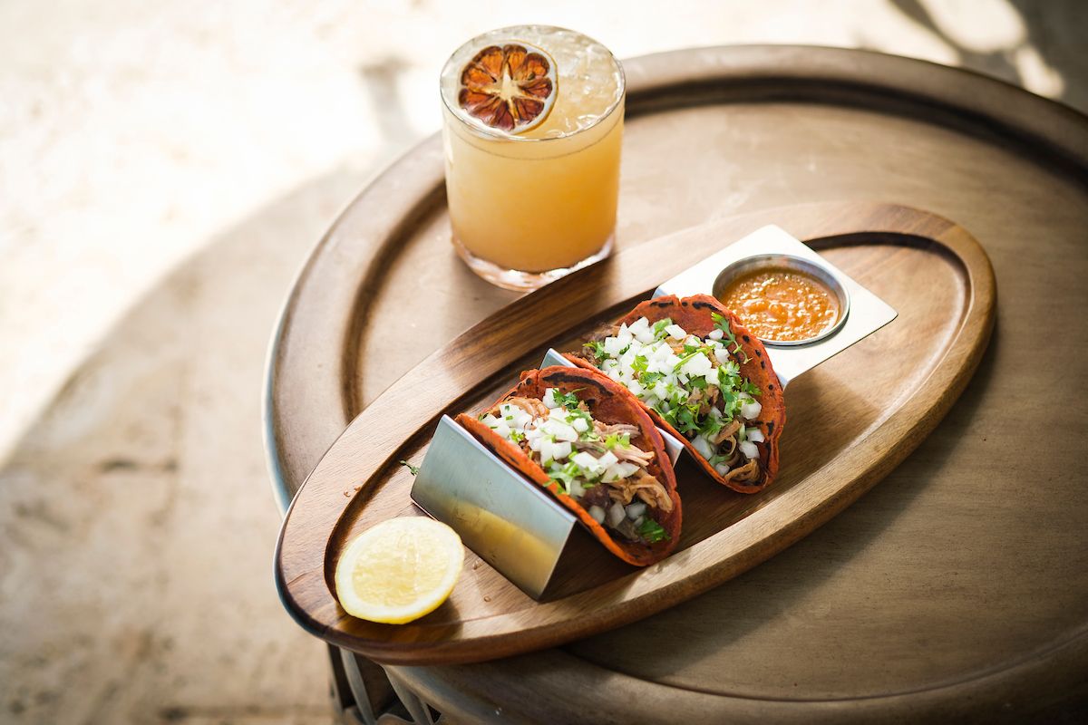 Gourmet tacos with herbs and onion, served with cocktail
