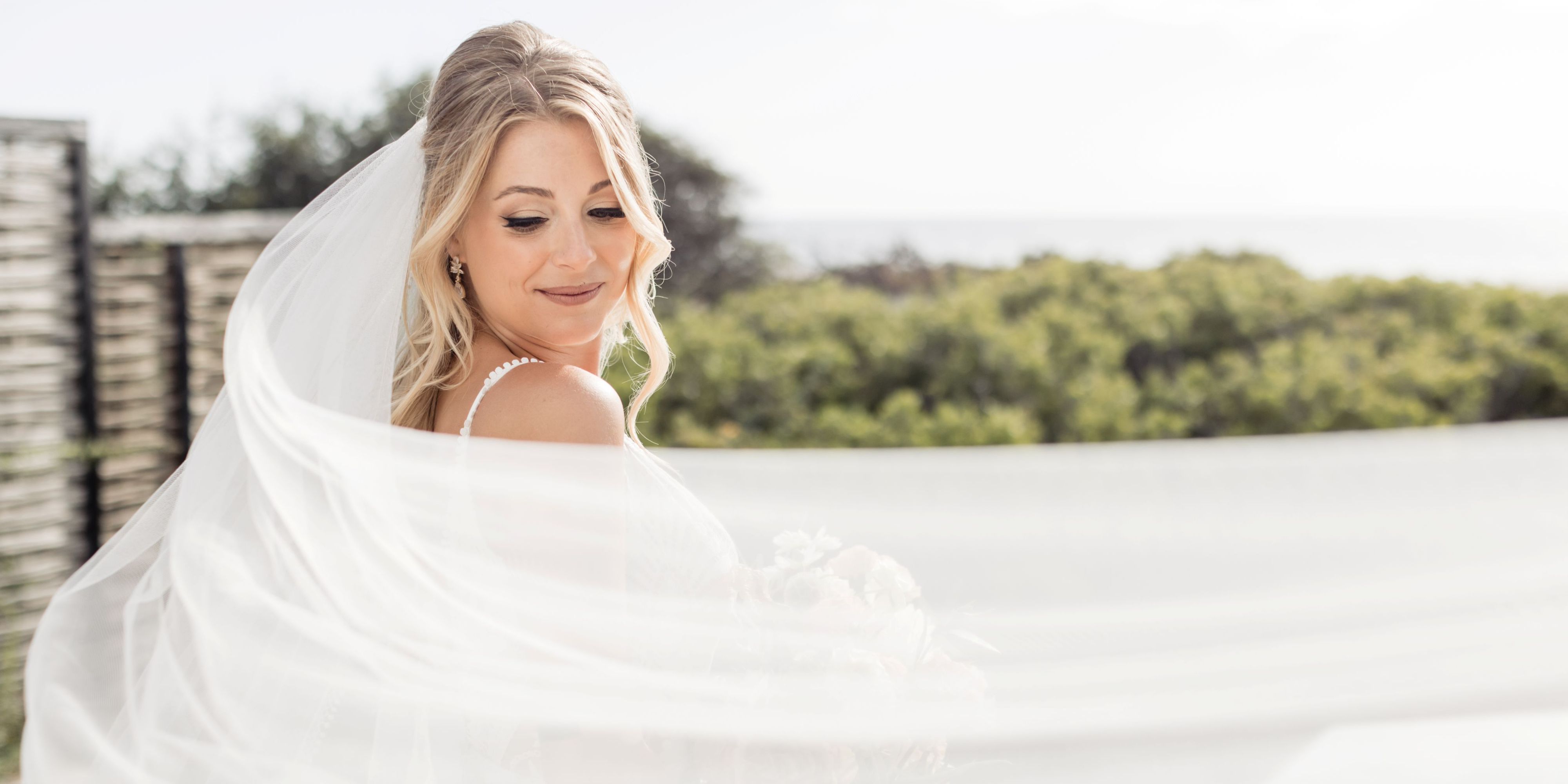 Bride with long veil posing for photo.