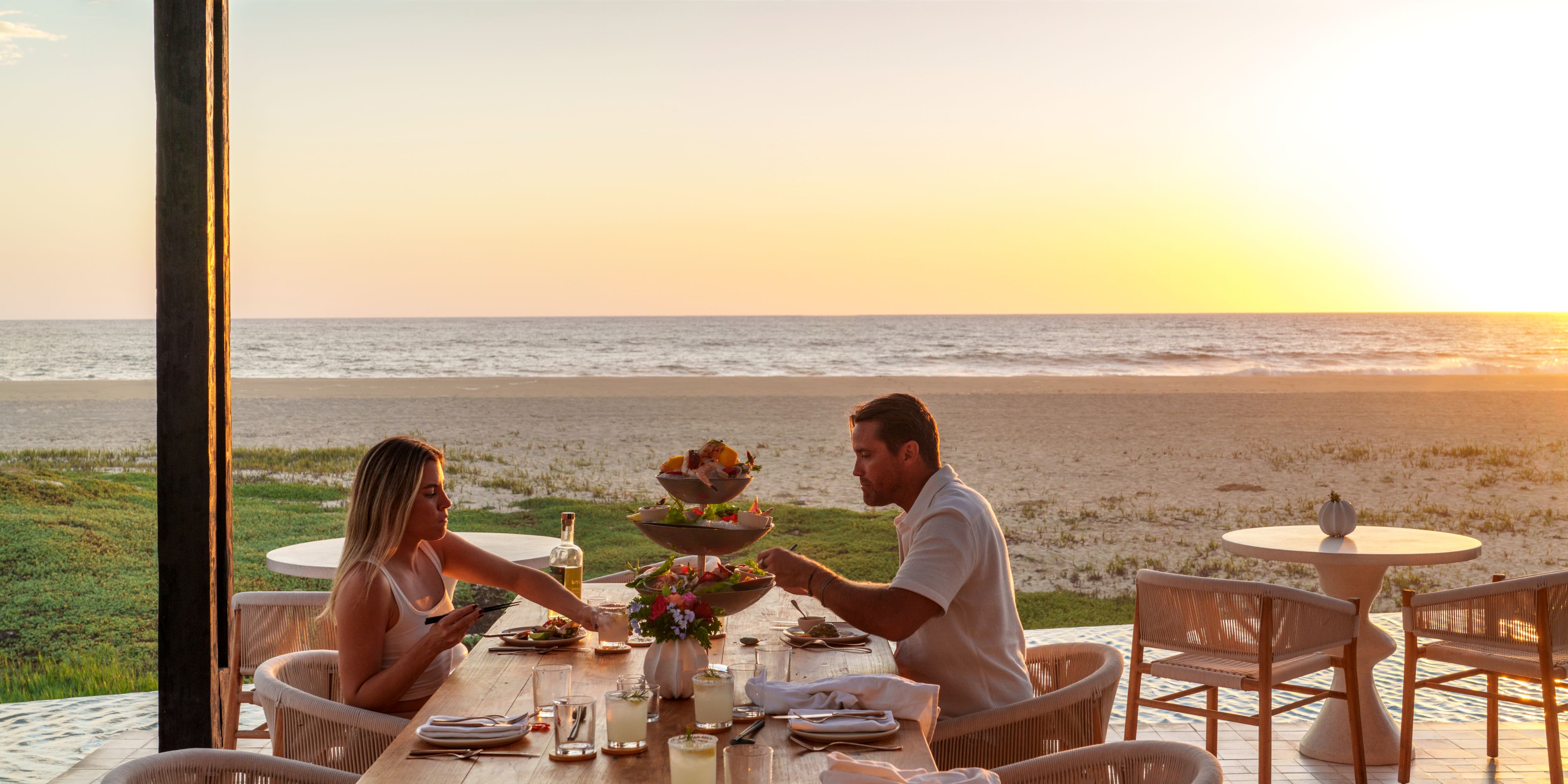 Couple dining by the beach with sunset views.