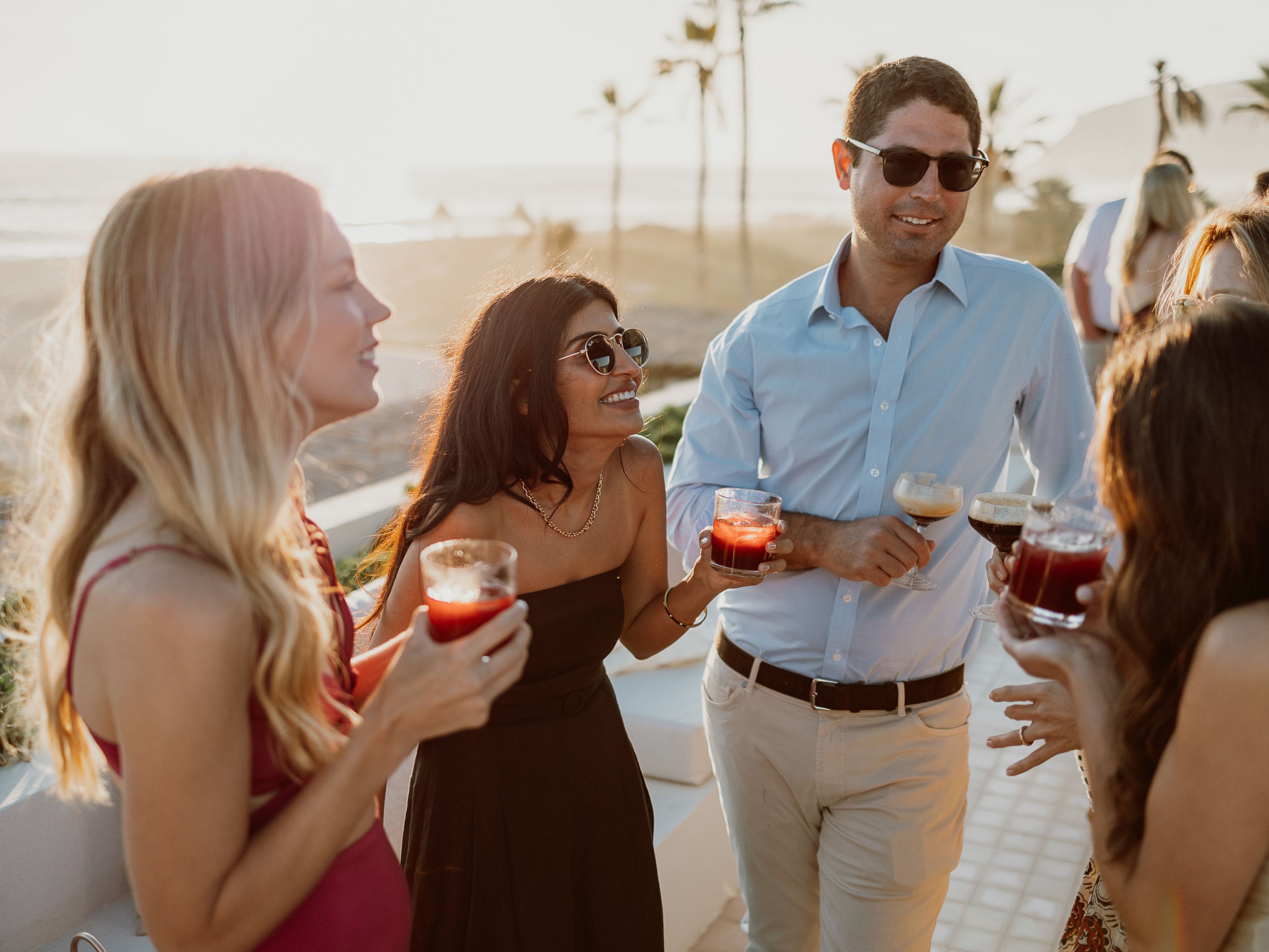 Friends standing in outdoor space at Kahal with cocktails in hand.