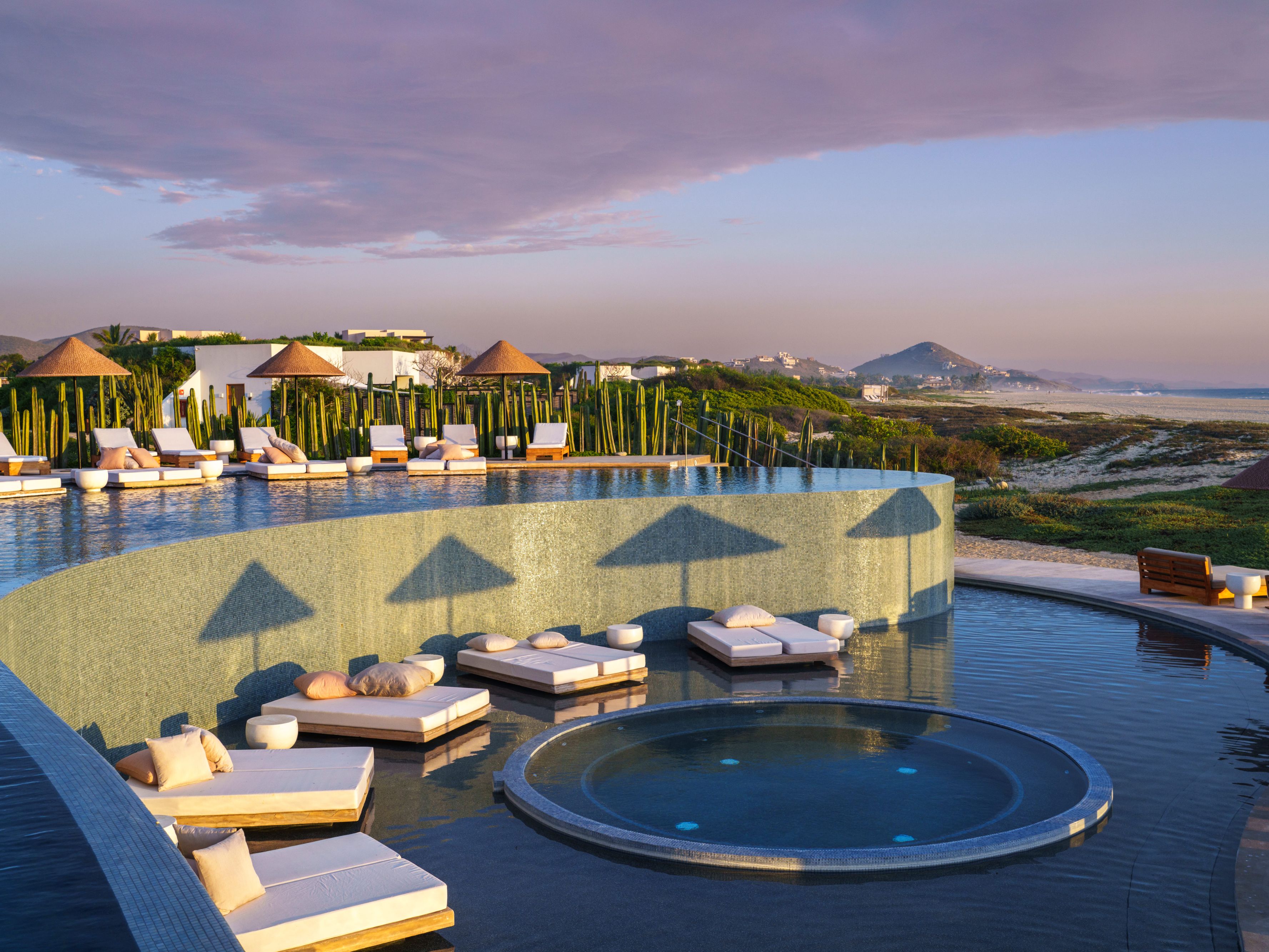 Pool with mountain and ocean views, stocked with cozy lounge chairs.
