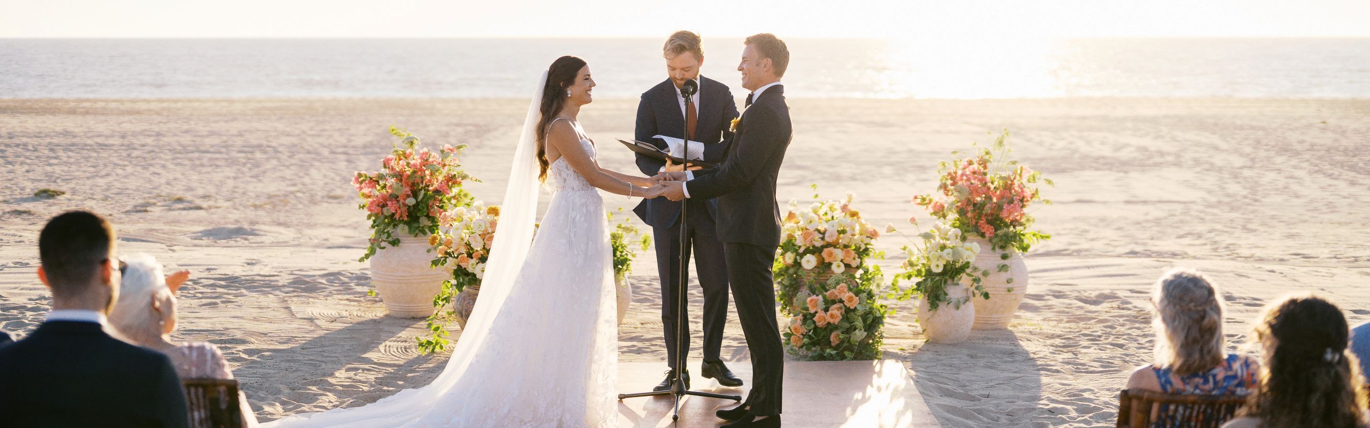 Bride and groom standing at alter on the beach during wedding.