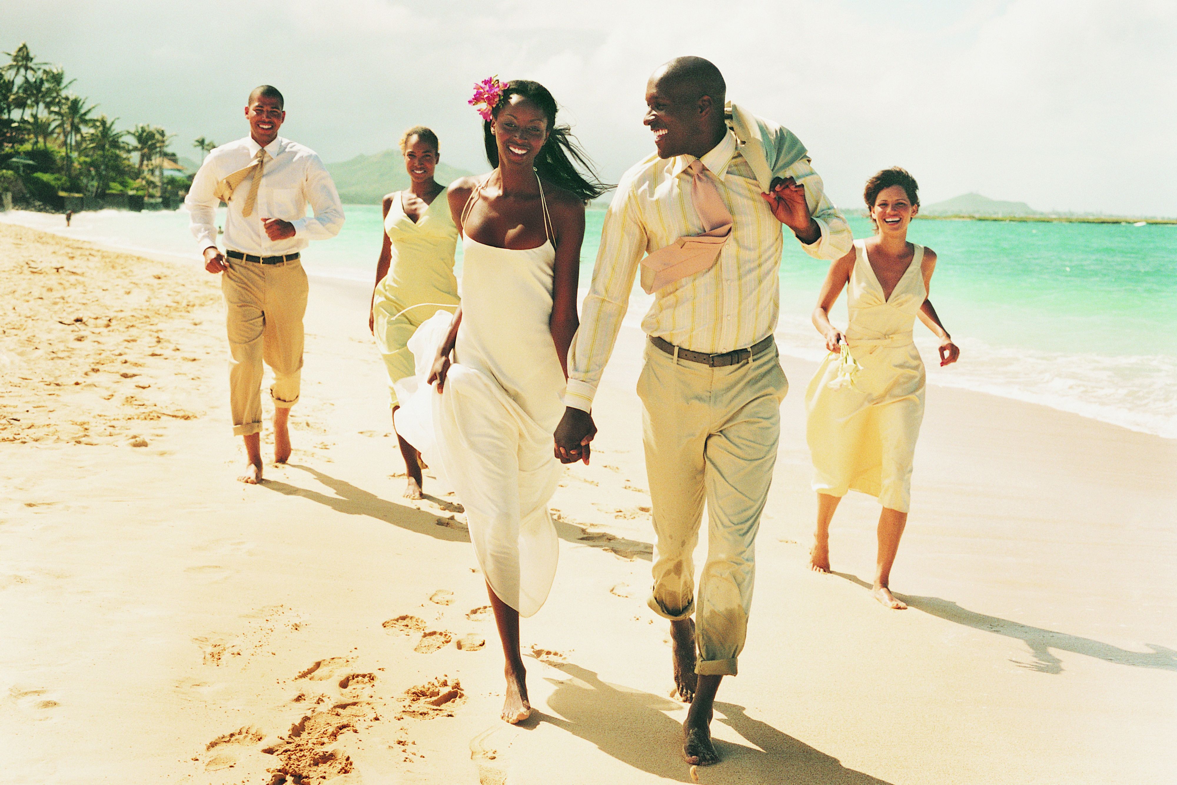 wedding couple on beach with wedding party in background