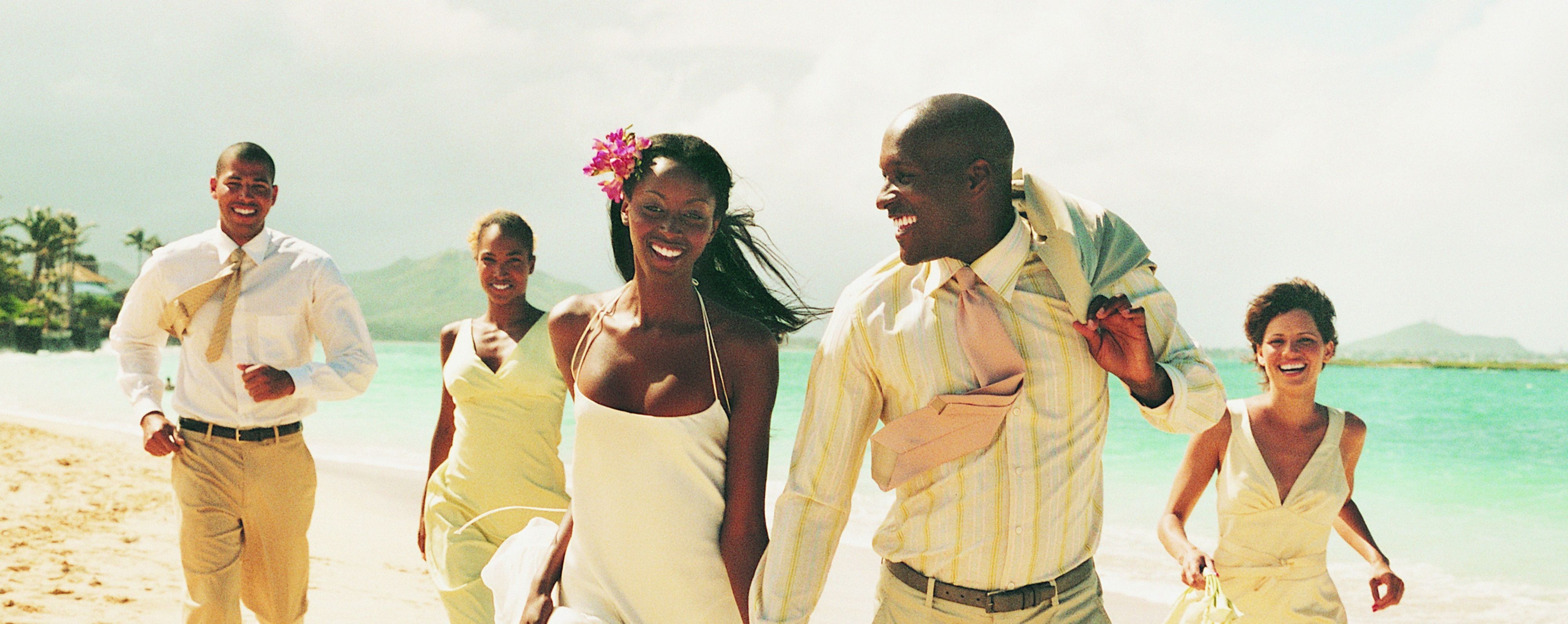 bride and groom at beach with wedding party