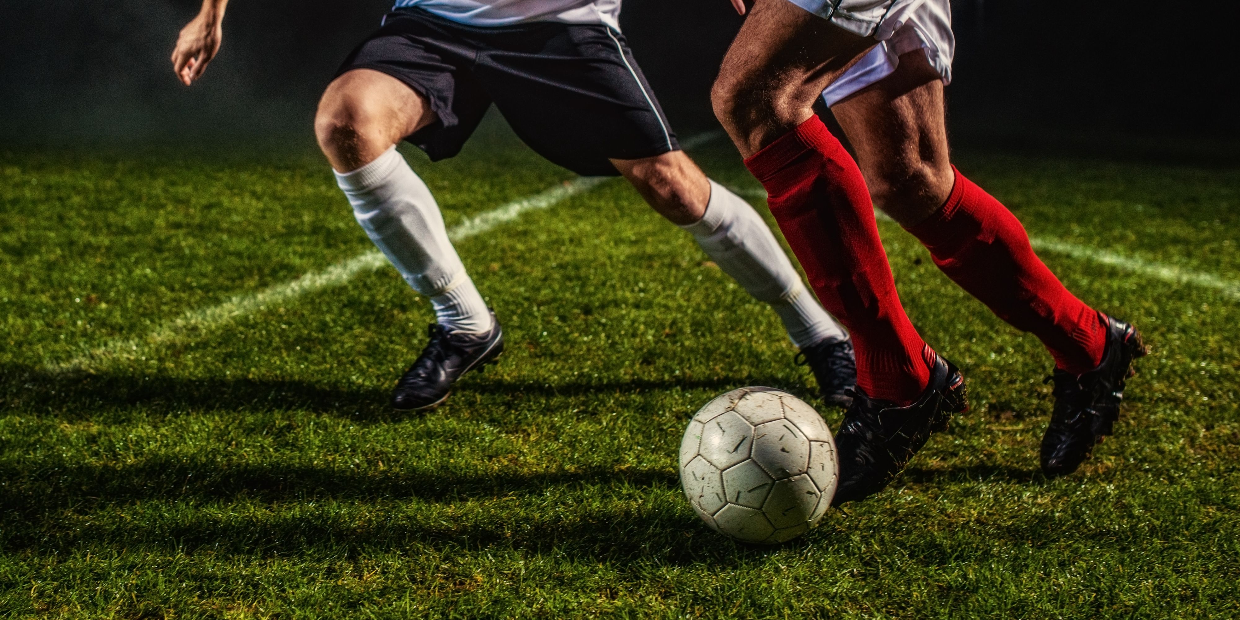 Soccer players kicking a ball.