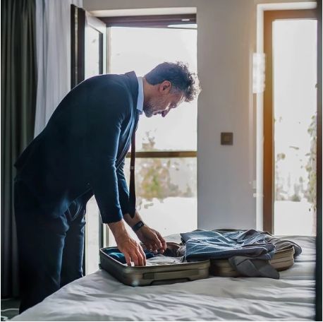 Man packing a suitcase on a bed