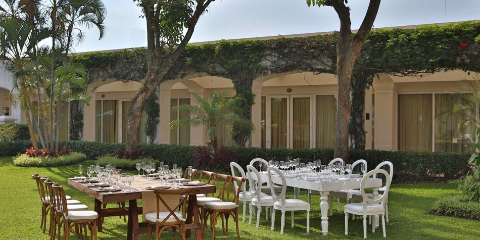 Disposición para bodas en el jardín con mesas largas y sillas blancas para ceremonias