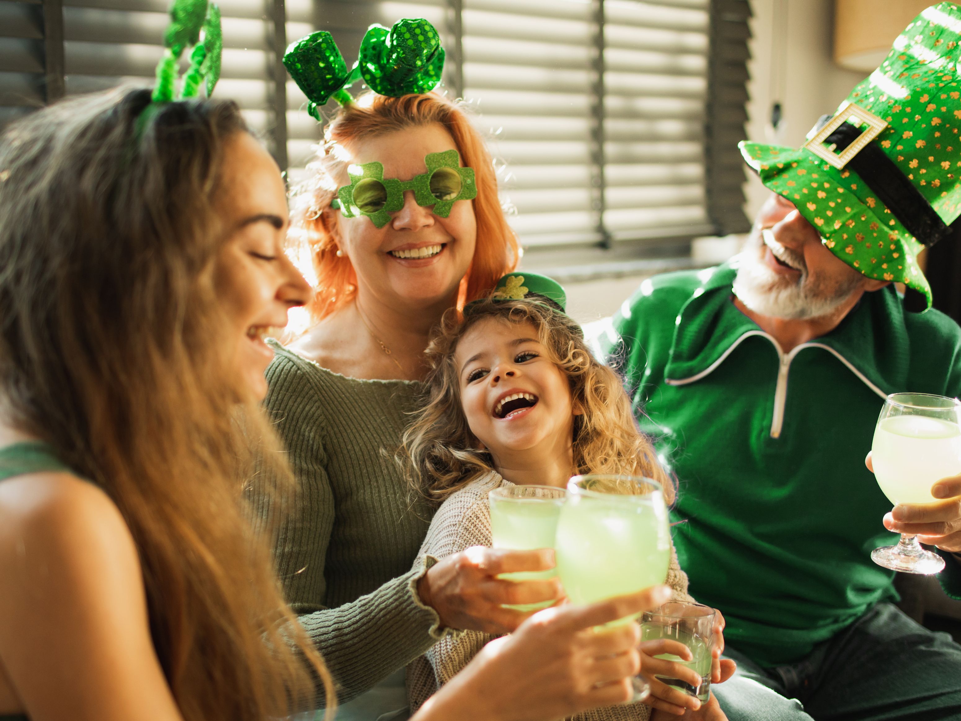 Family celebrating St. Patrick's Day with festive gear and drinks.