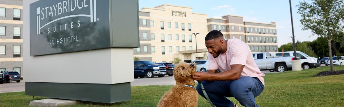 man and dog in front of staybridge hotels