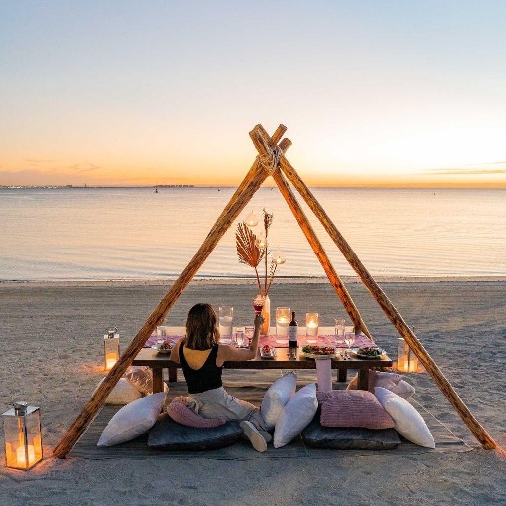 Guest eating dinner on beach while enjoying the sunset
