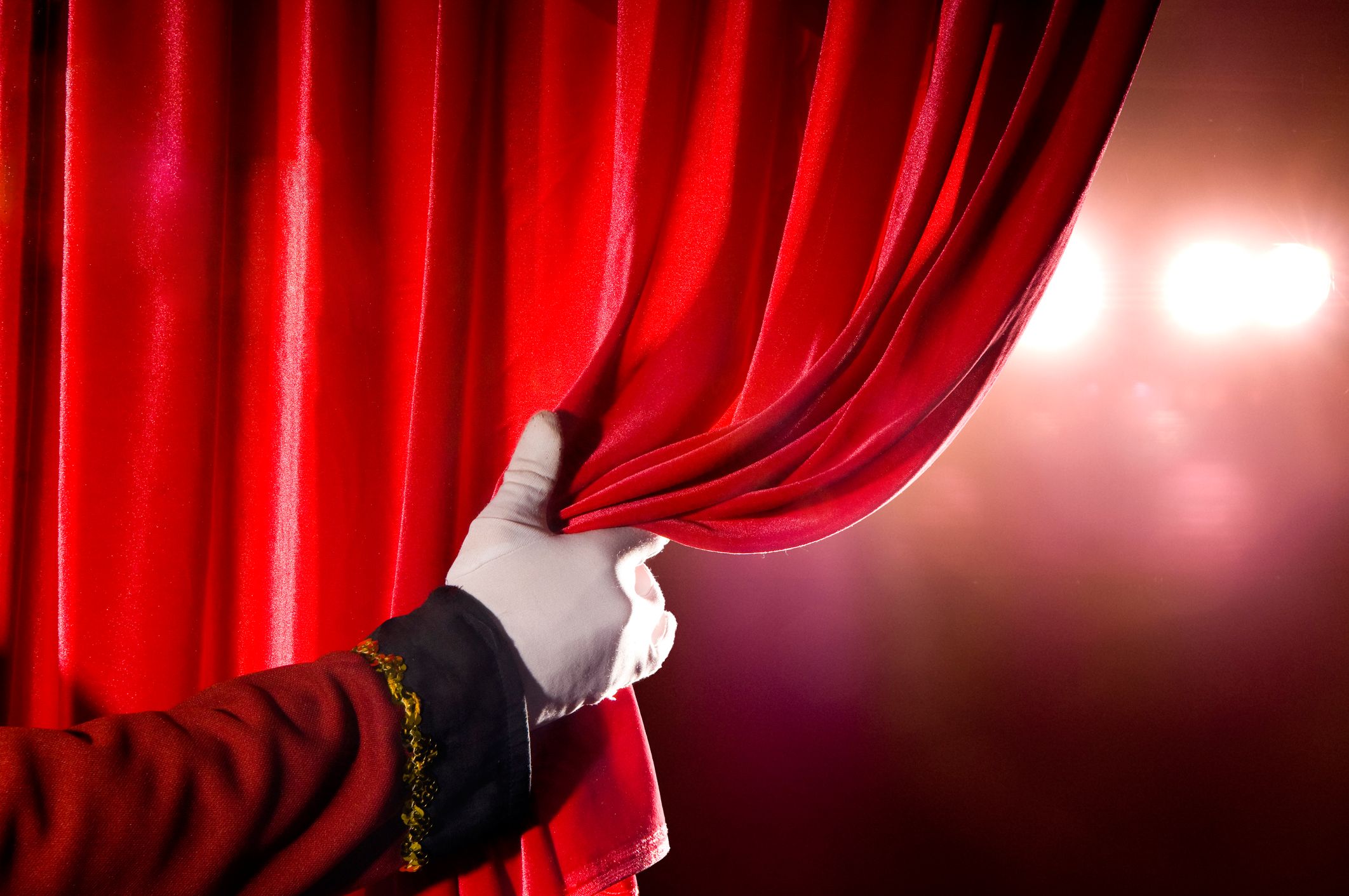 theater usher holding red curtain
