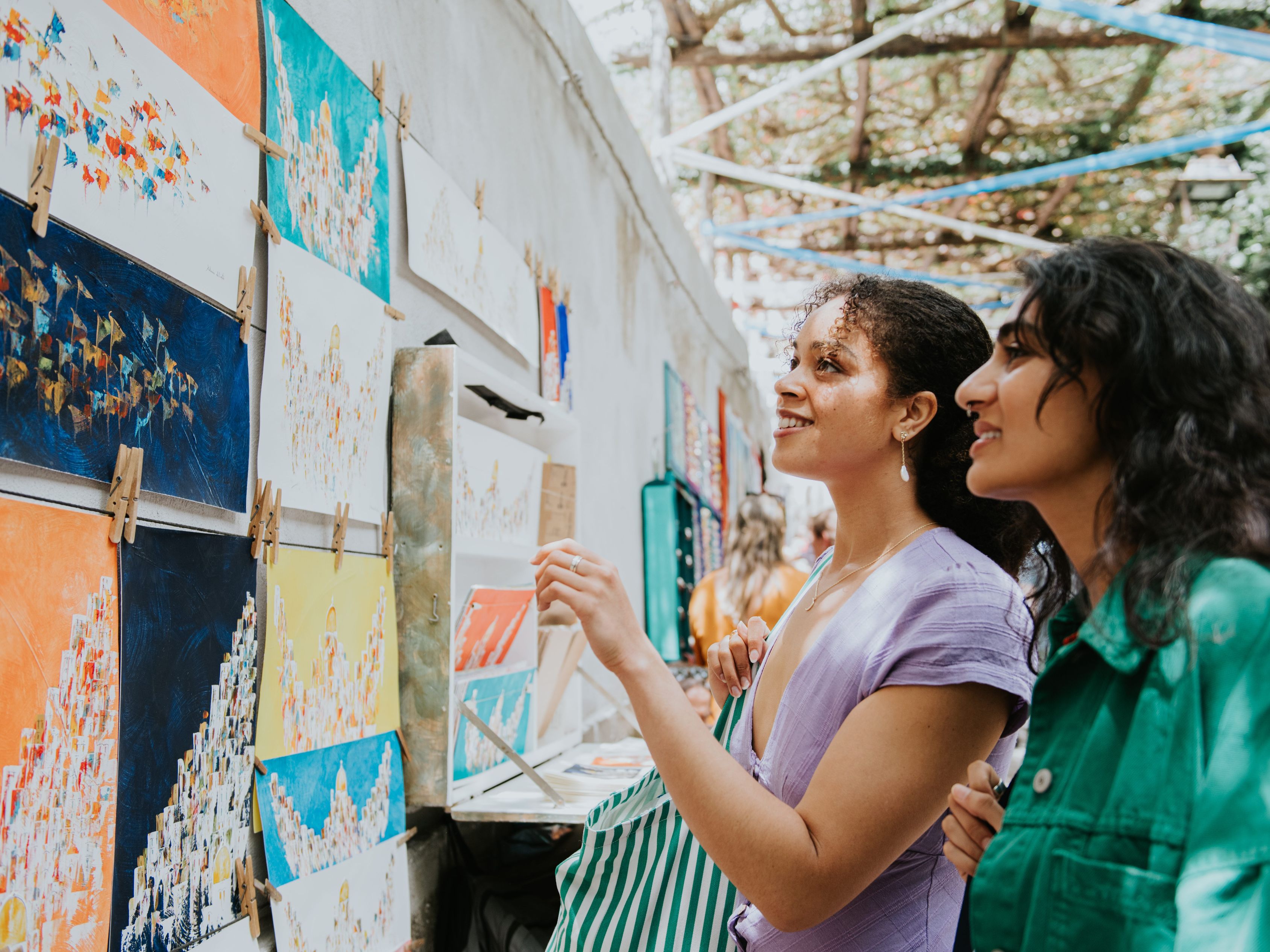 two women looking at art at market
