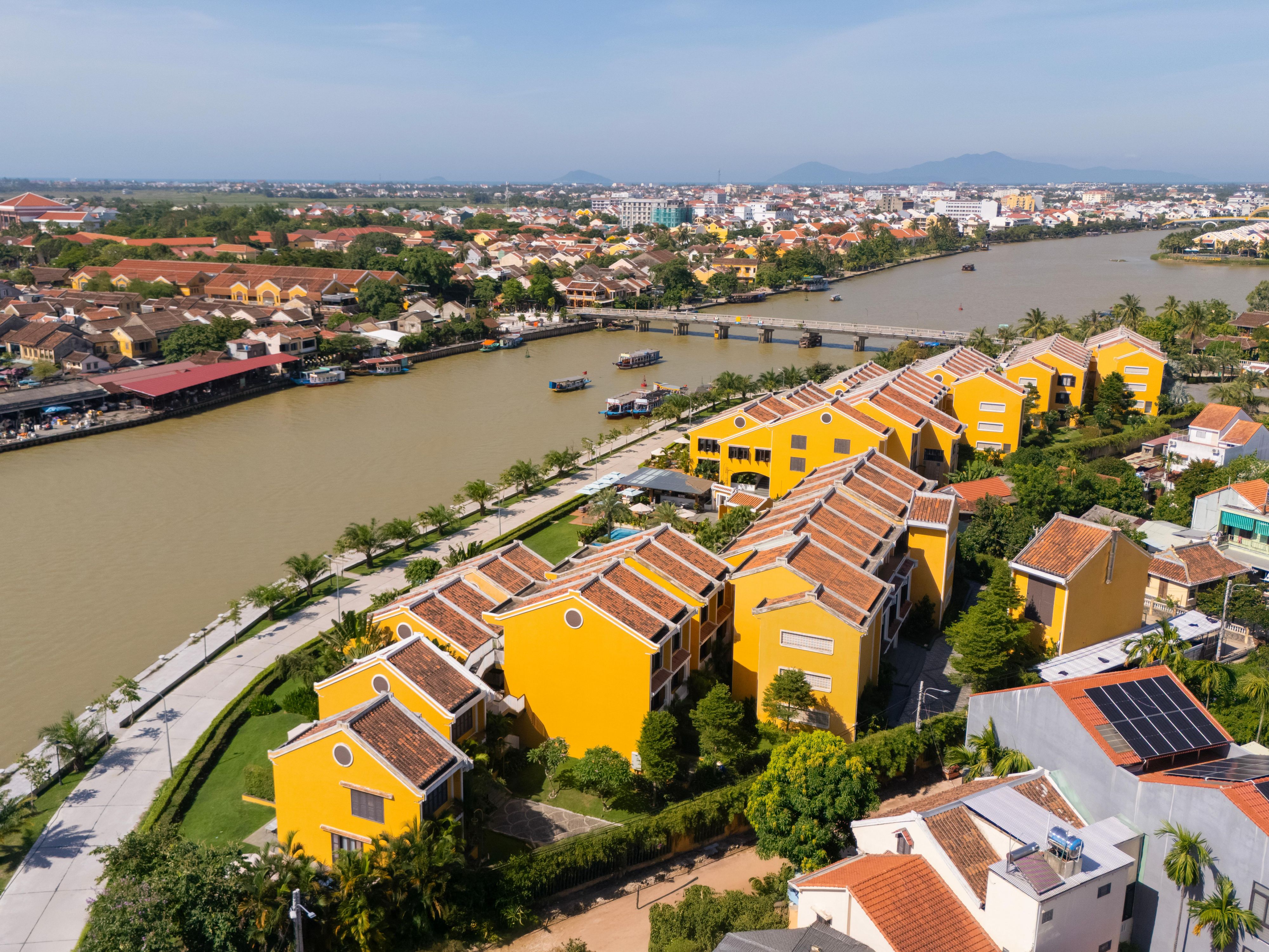 Moire Hoi An by day, with yellow walls along the river's edge.    