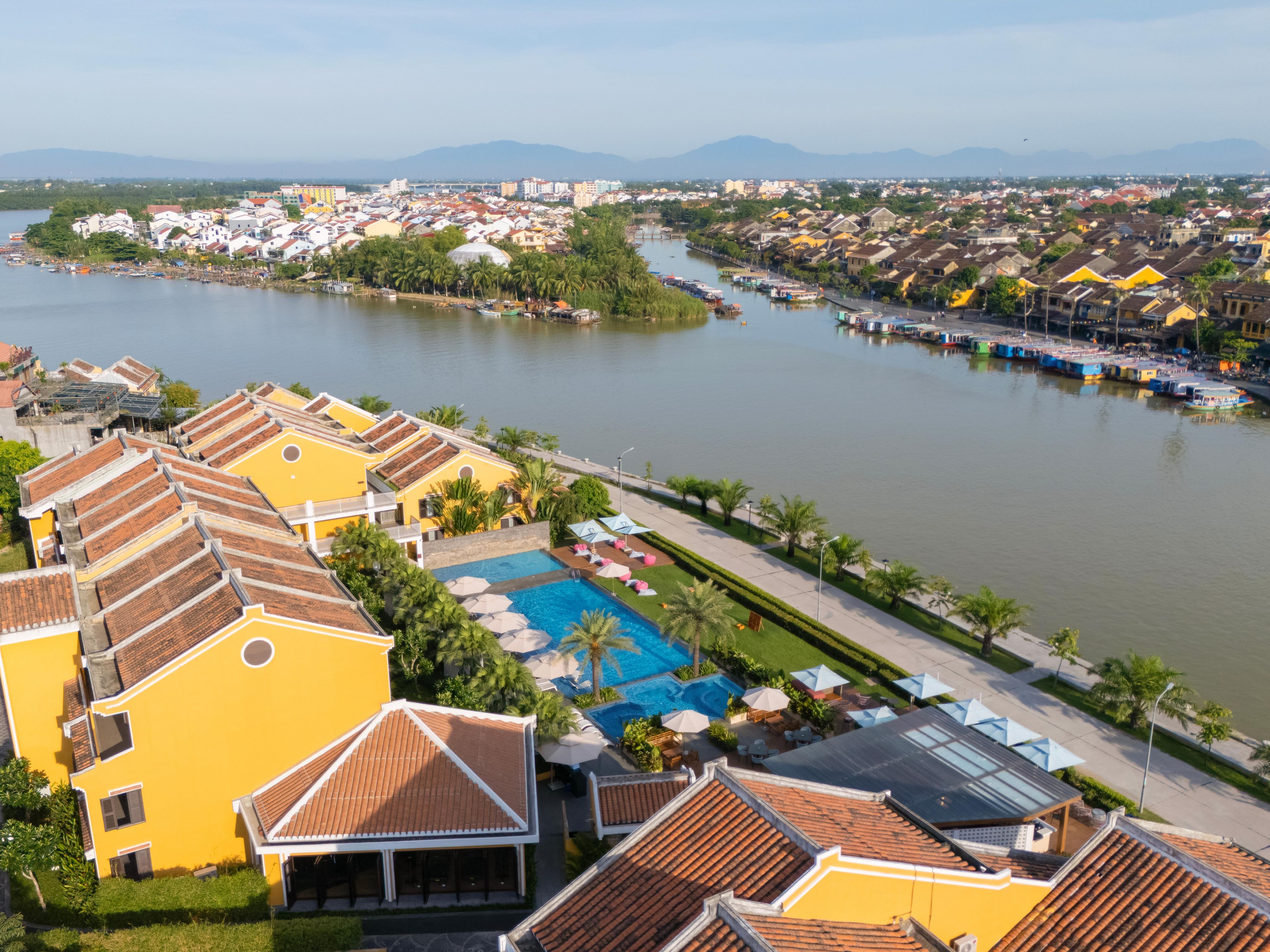 Lounge by the pool with captivating views of Hoi An’s riverside.  