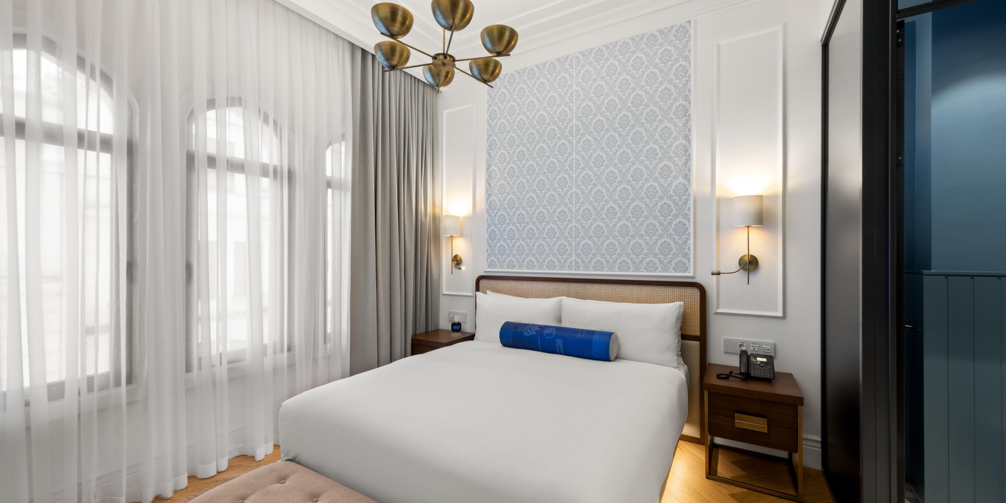 Rest easy on crisp white bedding beneath a warm brass chandelier