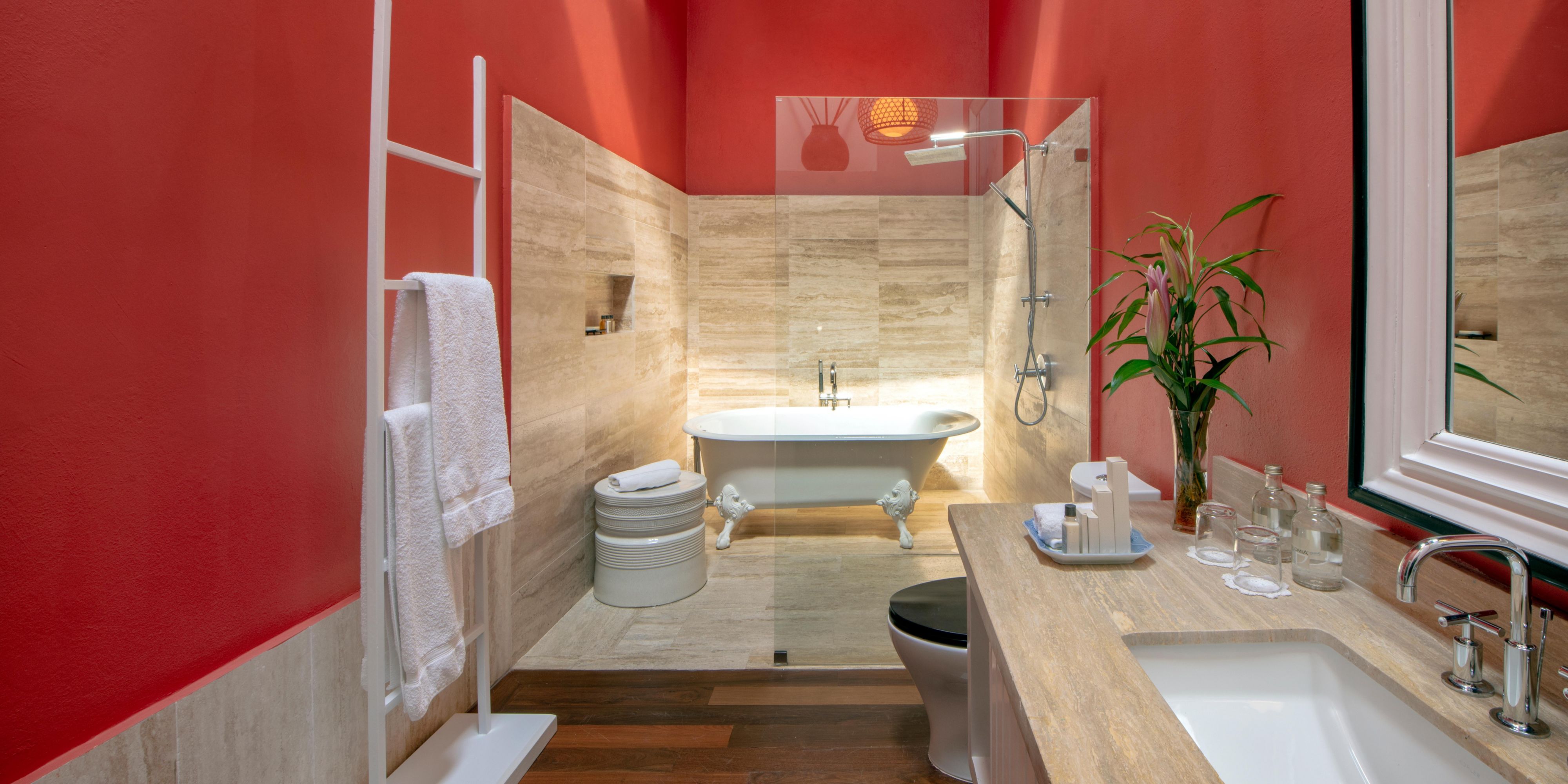 Modern bathroom with red walls, shower and freestanding tub.