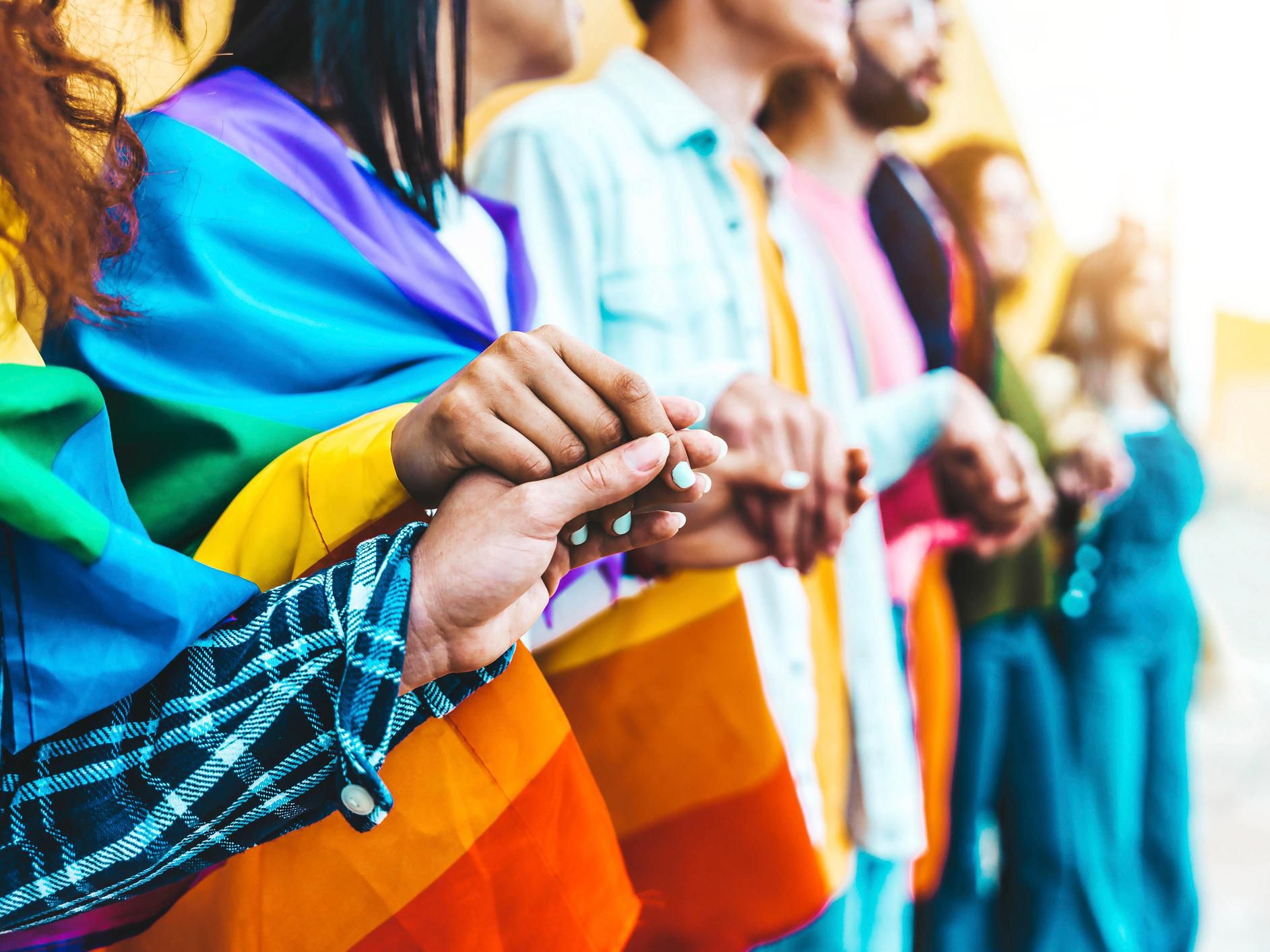 Participants in Pride holding hands and displaying rainbow colors.