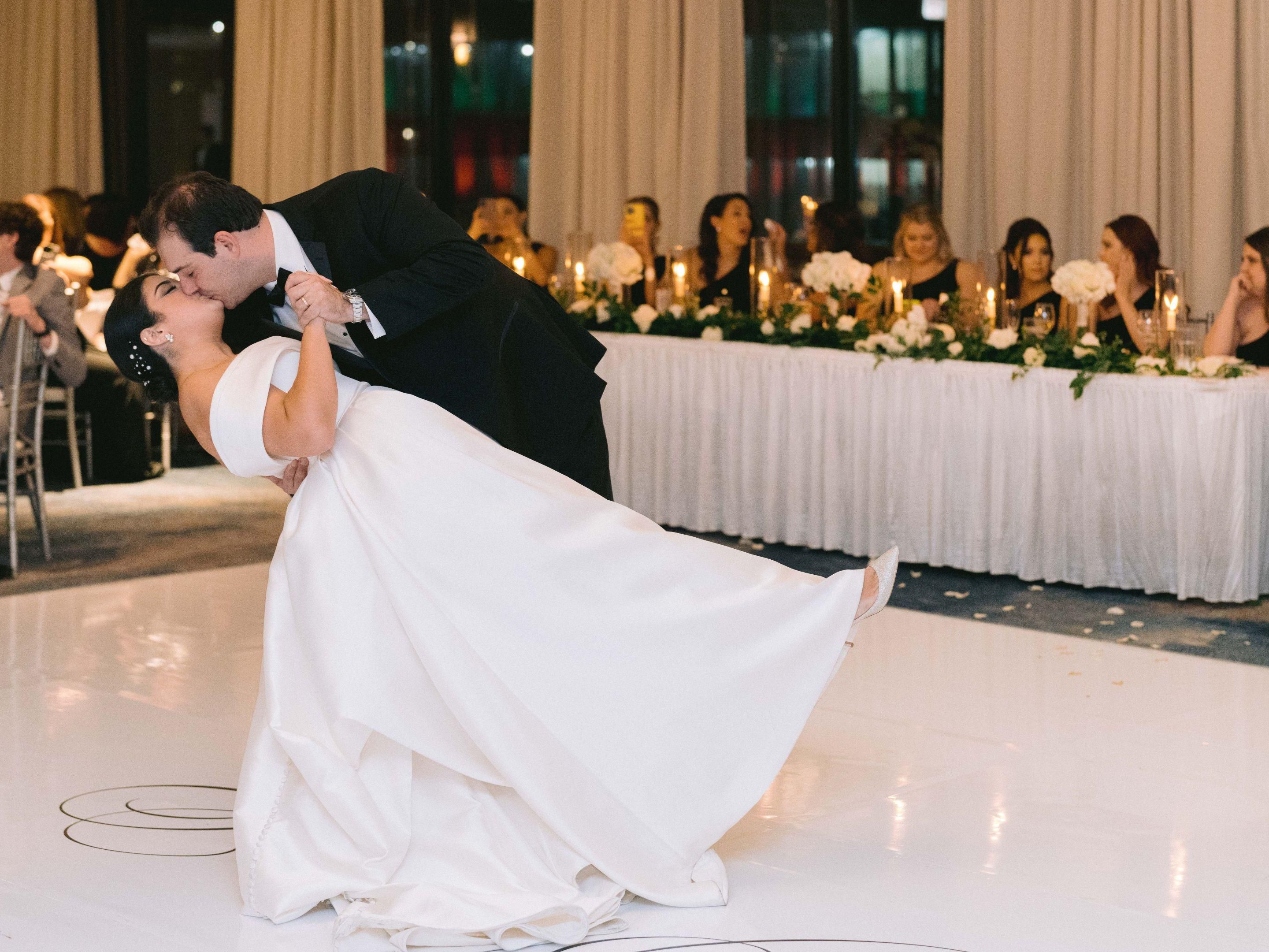 Groom dips bride in dance with a kiss