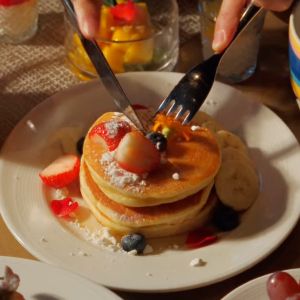 Pancake stack with strawberries, banana, and blueberries.