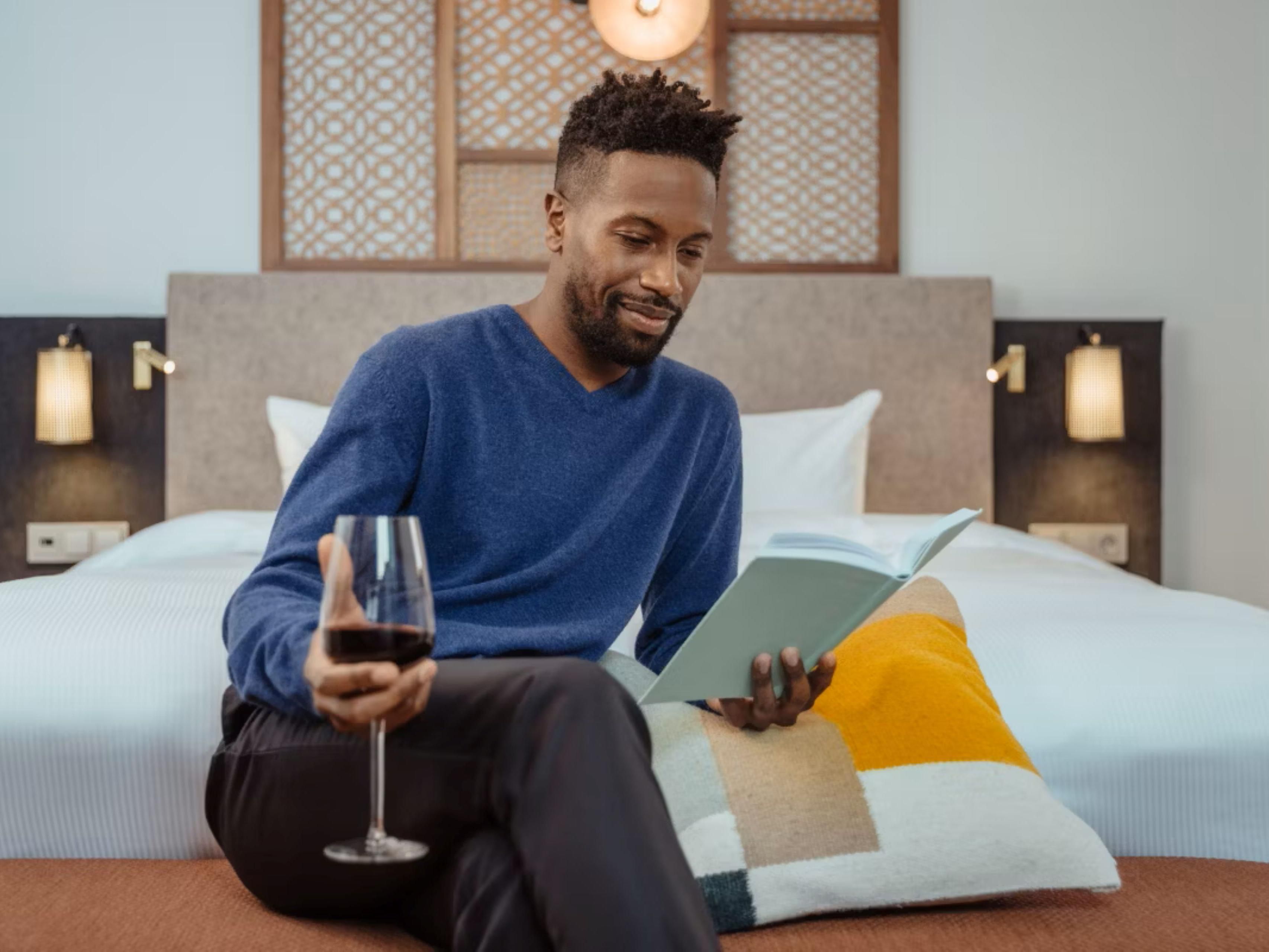 Man with a glass of wine reading a book