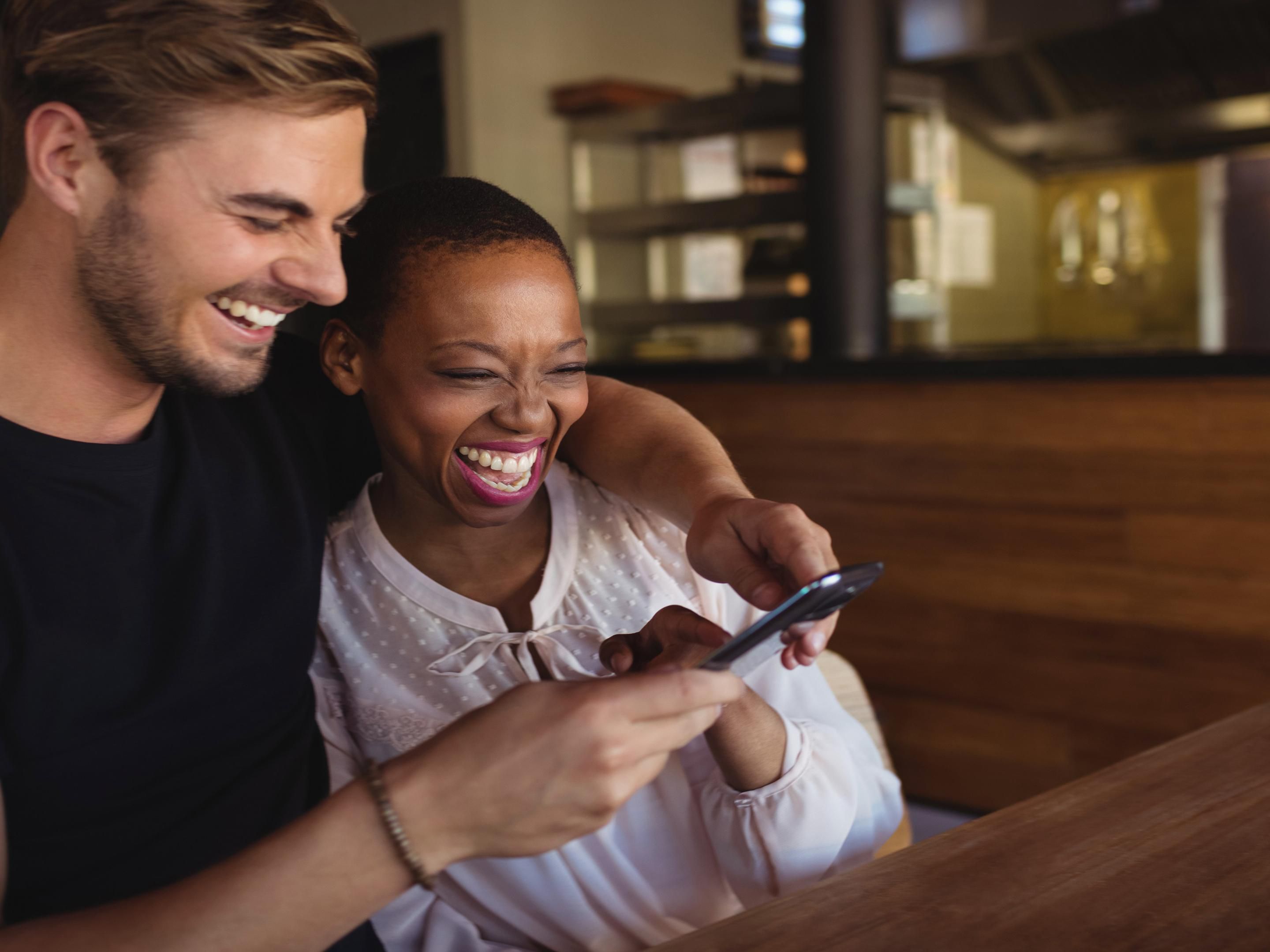 Couple laughing and looking at a phone