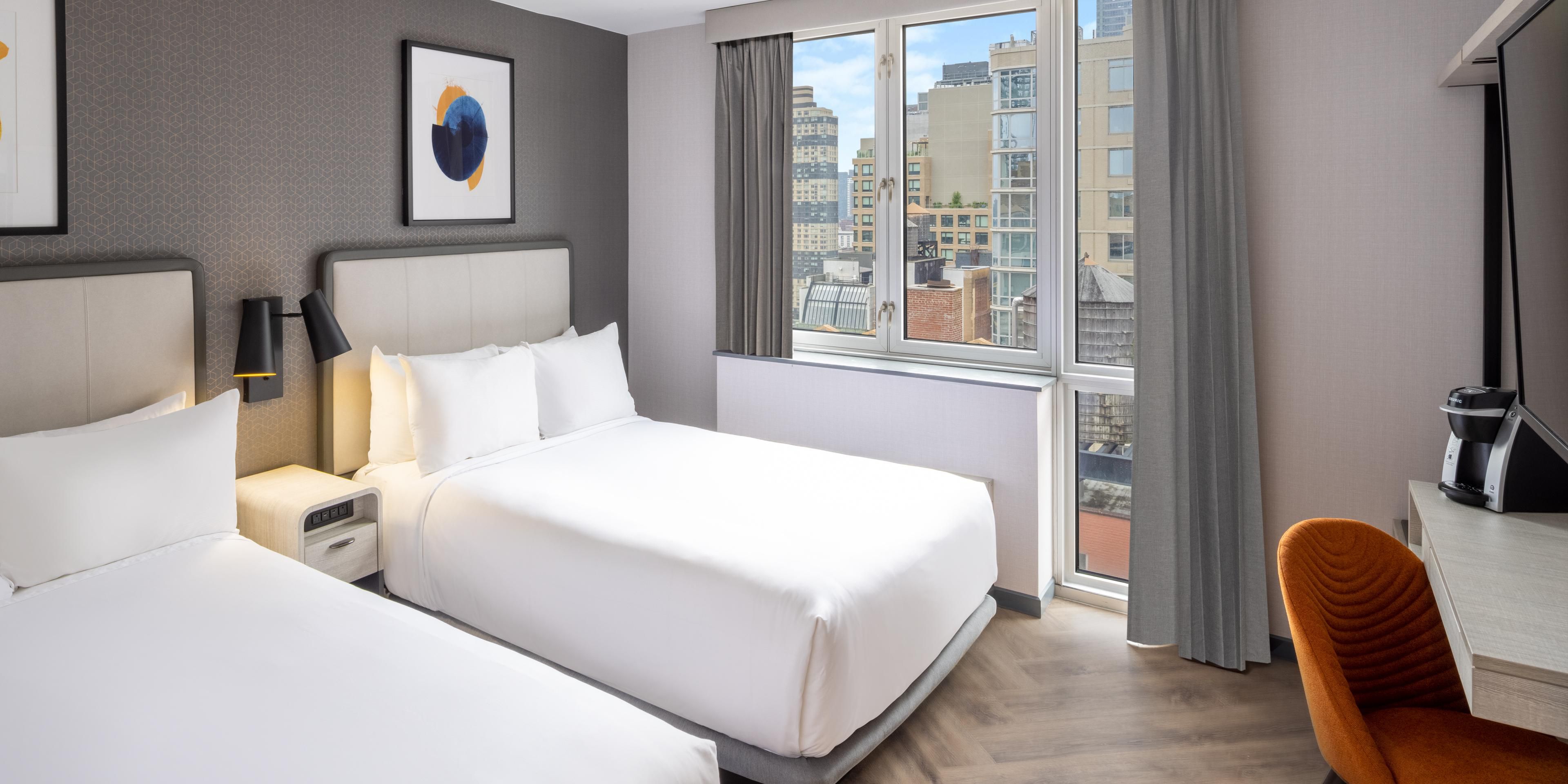 Renovated guest room with two double beds and views of Manhattan.