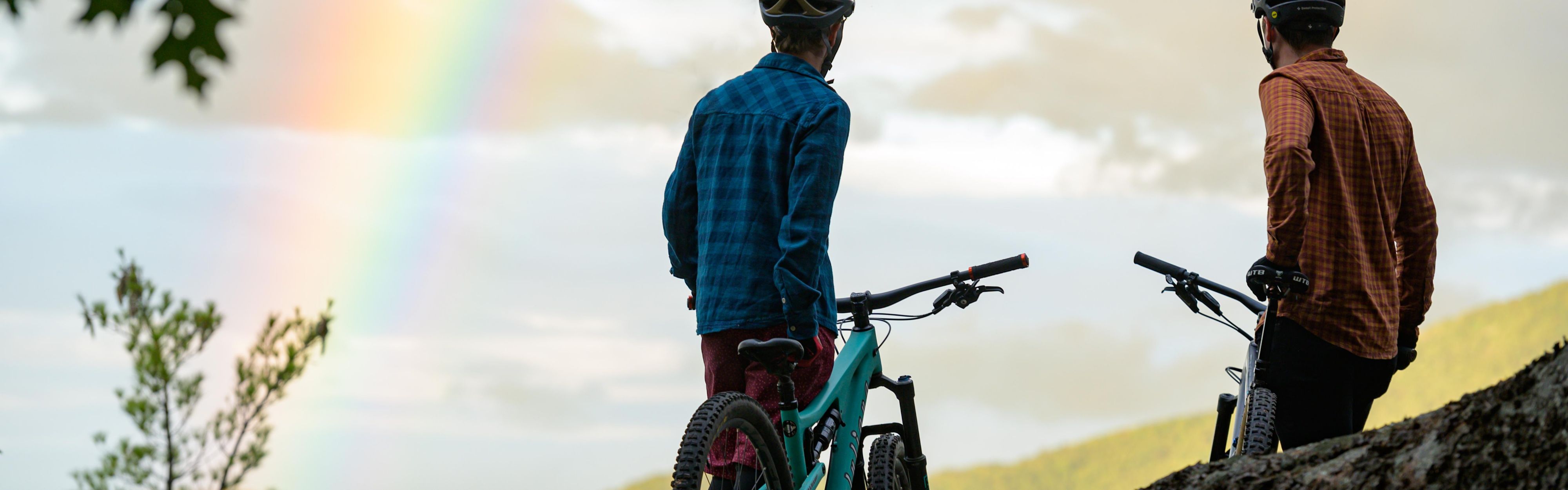 Men standing mountaintop with their bikes.