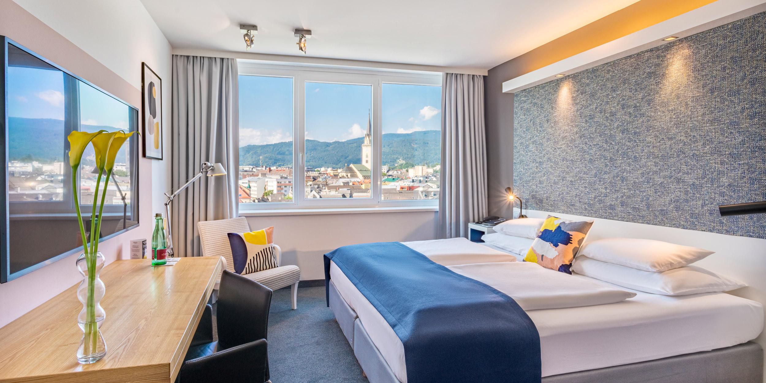 Genieße pure Eleganz in unseren Premium Zimmer mit atemberaubendem Draublick im voco Villach. Dieses exklusive Refugium vereint modernen Komfort mit einer malerischen Aussicht auf die Drau und die Stadt Villach. Entspanne im stilvollen Ambiente und erlebe erstklassige Annehmlichkeiten, die deinen Aufenthalt unvergesslich machen.