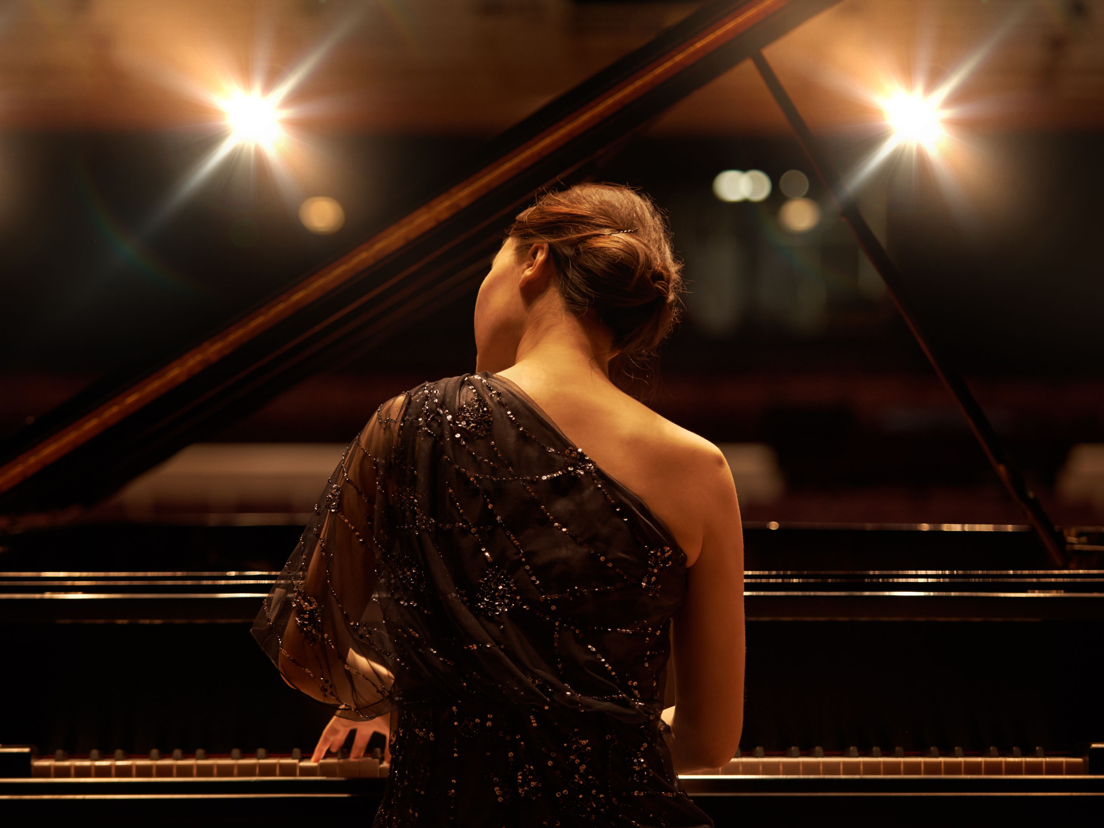 woman sitting and playing the piano on a stage